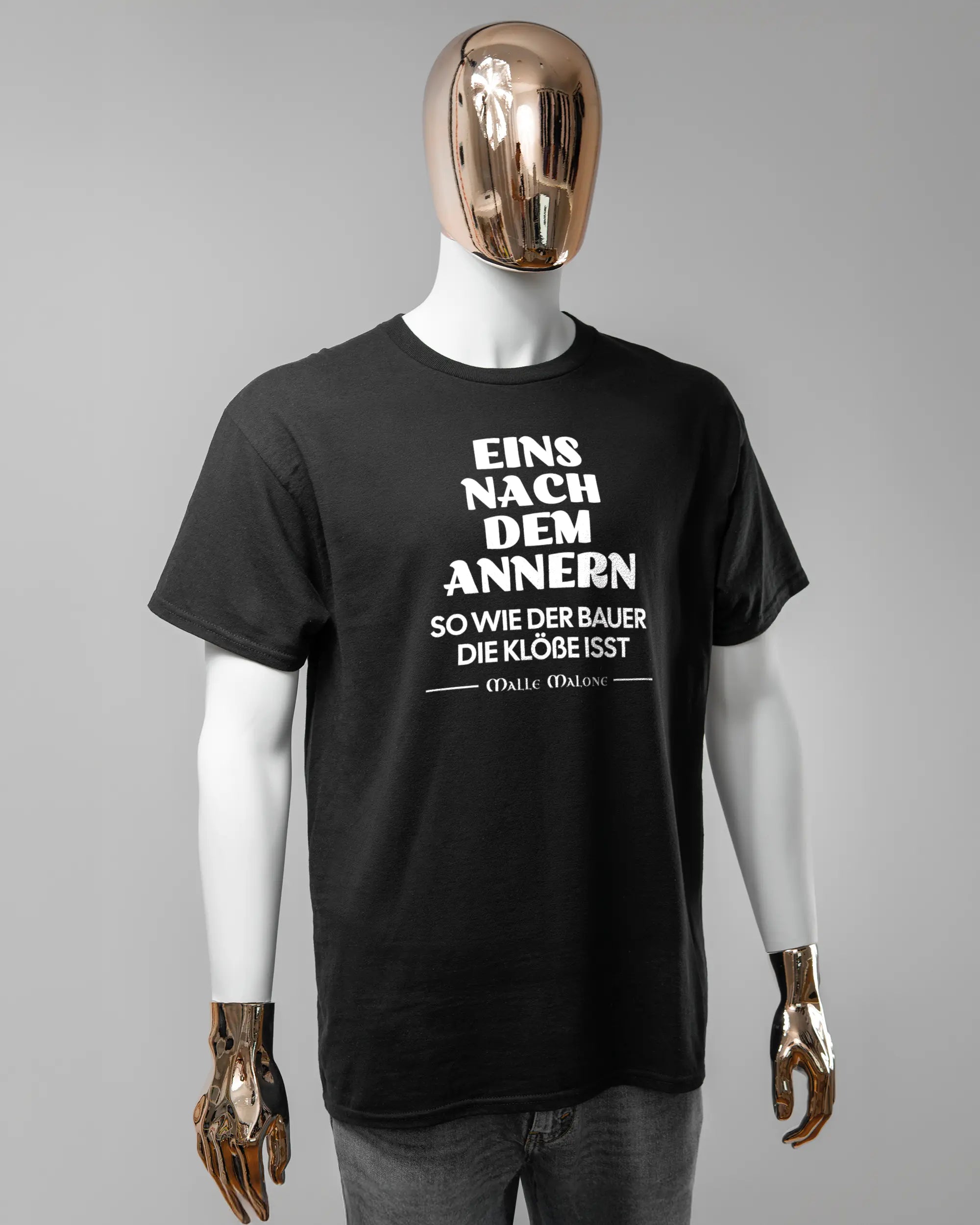 Vorderseite des Basic Unisex T-Shirt Regular von Maondo mit dem Design Eins nach dem Annern in der Farbe Black und in der Größe L getragen von einer maskulinen Puppe