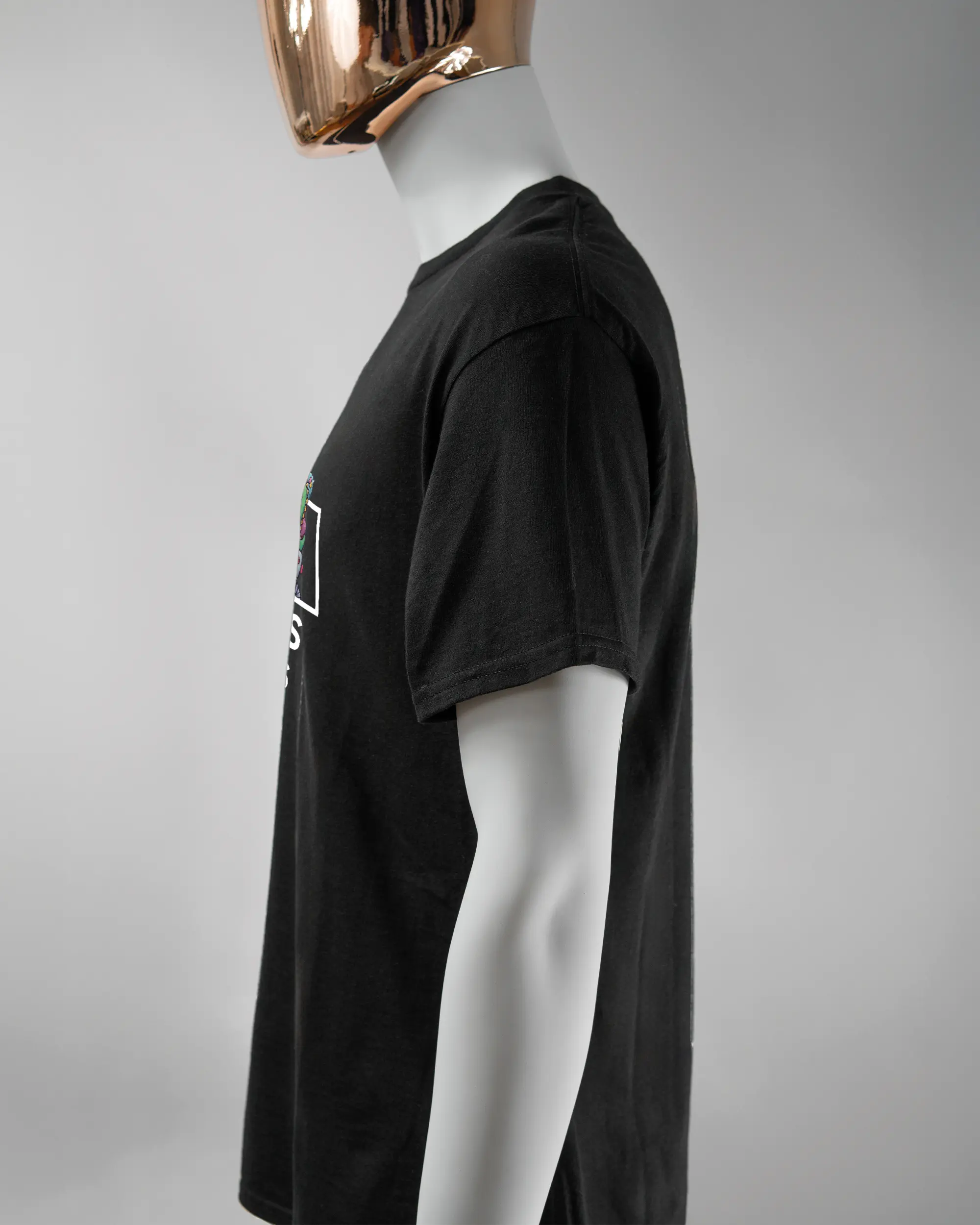 Seitenansicht des Basic Unisex T-Shirt Regular von Maondo mit dem Design Will Stofftier vorne in der Farbe Black und in der Größe L getragen von einer maskulinen Puppe