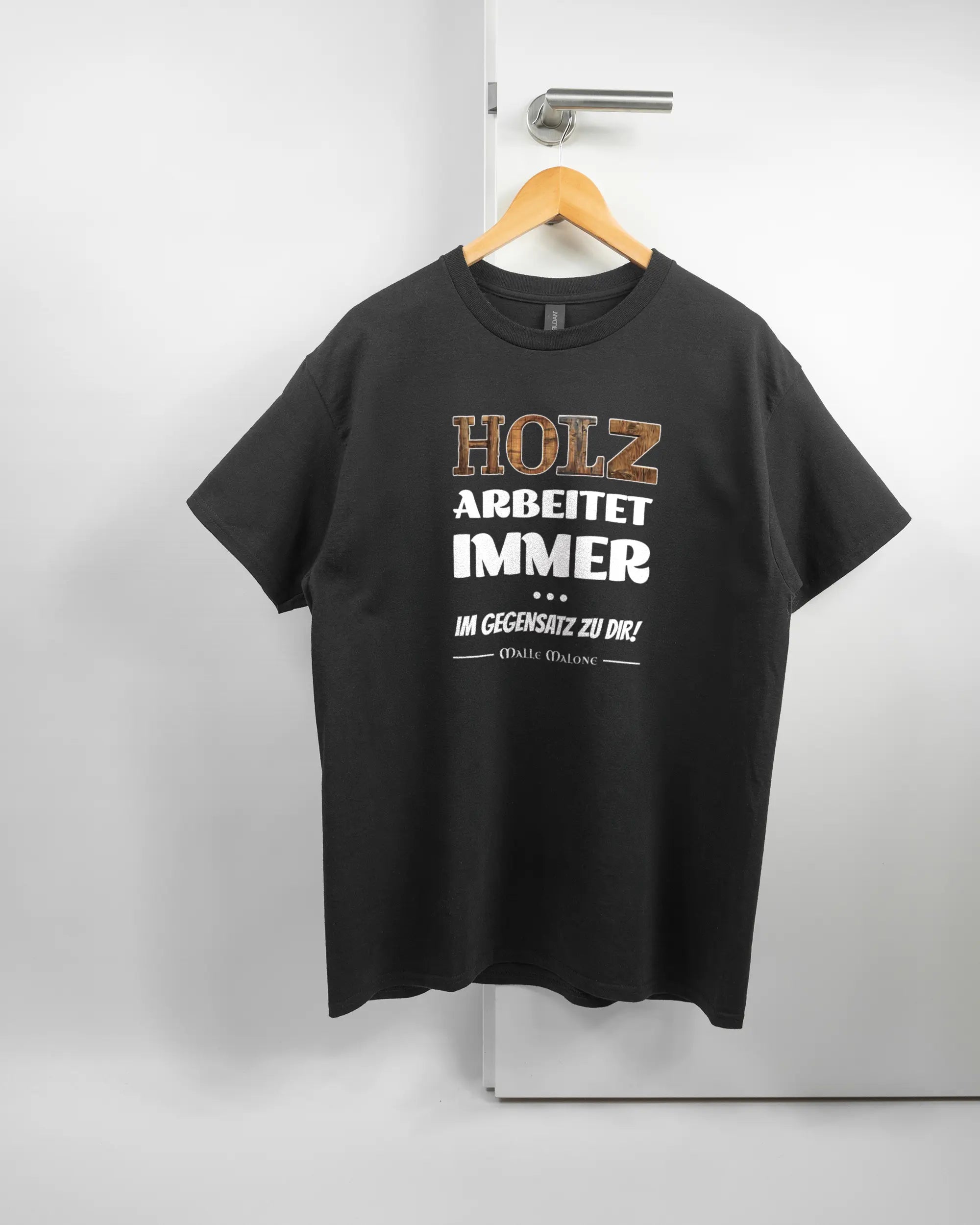 Vorderseite des Basic Unisex T-Shirt Regular von Maondo mit dem Design Holzarbeit in der Farbe Black und in der Größe L auf einem Bügel an der Türklinke aufgehängt