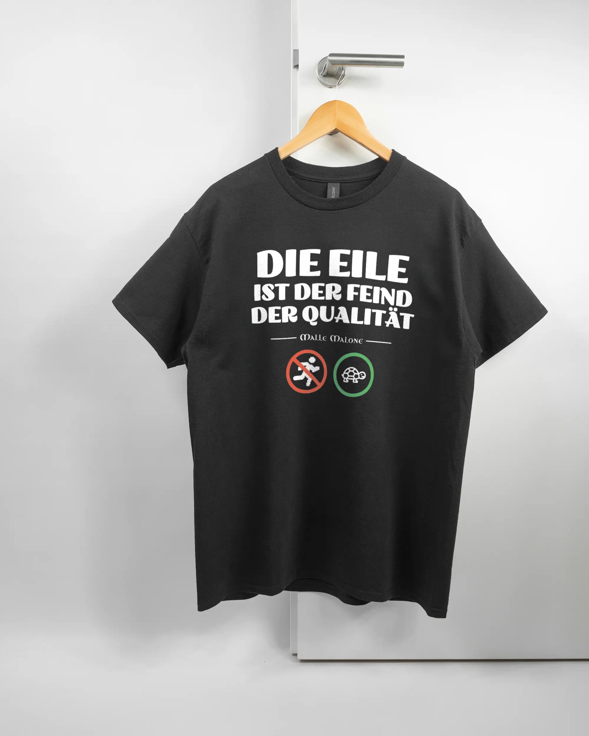 Vorderseite des Basic Unisex T-Shirt Regular von Maondo mit dem Design Keine Eile in der Farbe Black und in der Größe L auf einem Bügel an der Türklinke aufgehängt