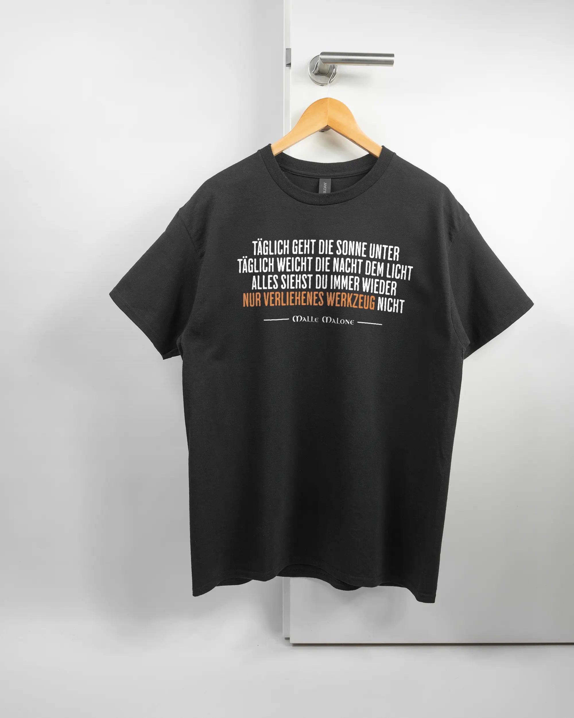 Vorderseite des Basic Unisex T-Shirt Regular von Maondo mit dem Design Wegzeug in der Farbe Black und in der Größe L auf einem Bügel an der Türklinke aufgehängt