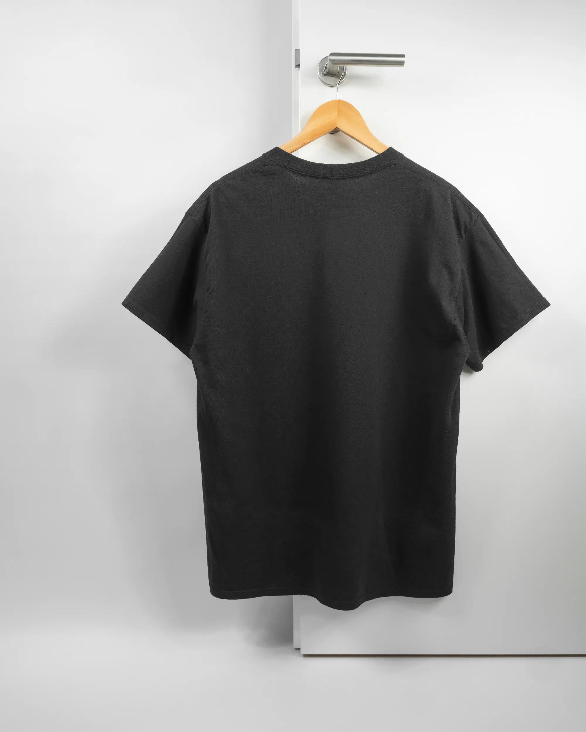 Rückseite des Basic Unisex T-Shirt Regular von Maondo ohne Motiv in der Farbe Black und in der Größe L auf einem Bügel an der Türklinke aufgehängt