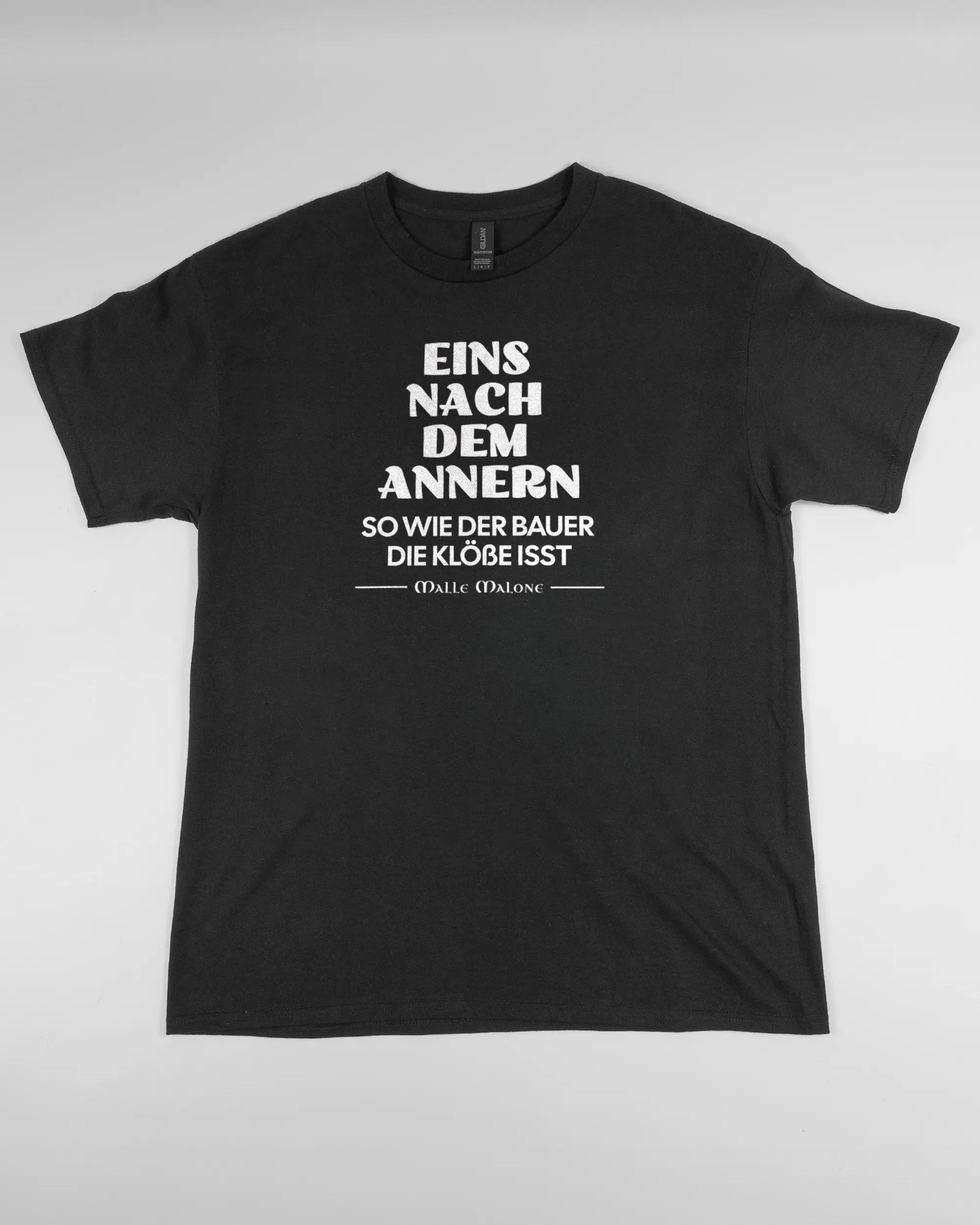 Vorderseite des Basic Unisex T-Shirt Regular von Maondo mit dem Design Eins nach dem Annern in der Farbe Black und in der Größe L flach auf den Boden gelegt