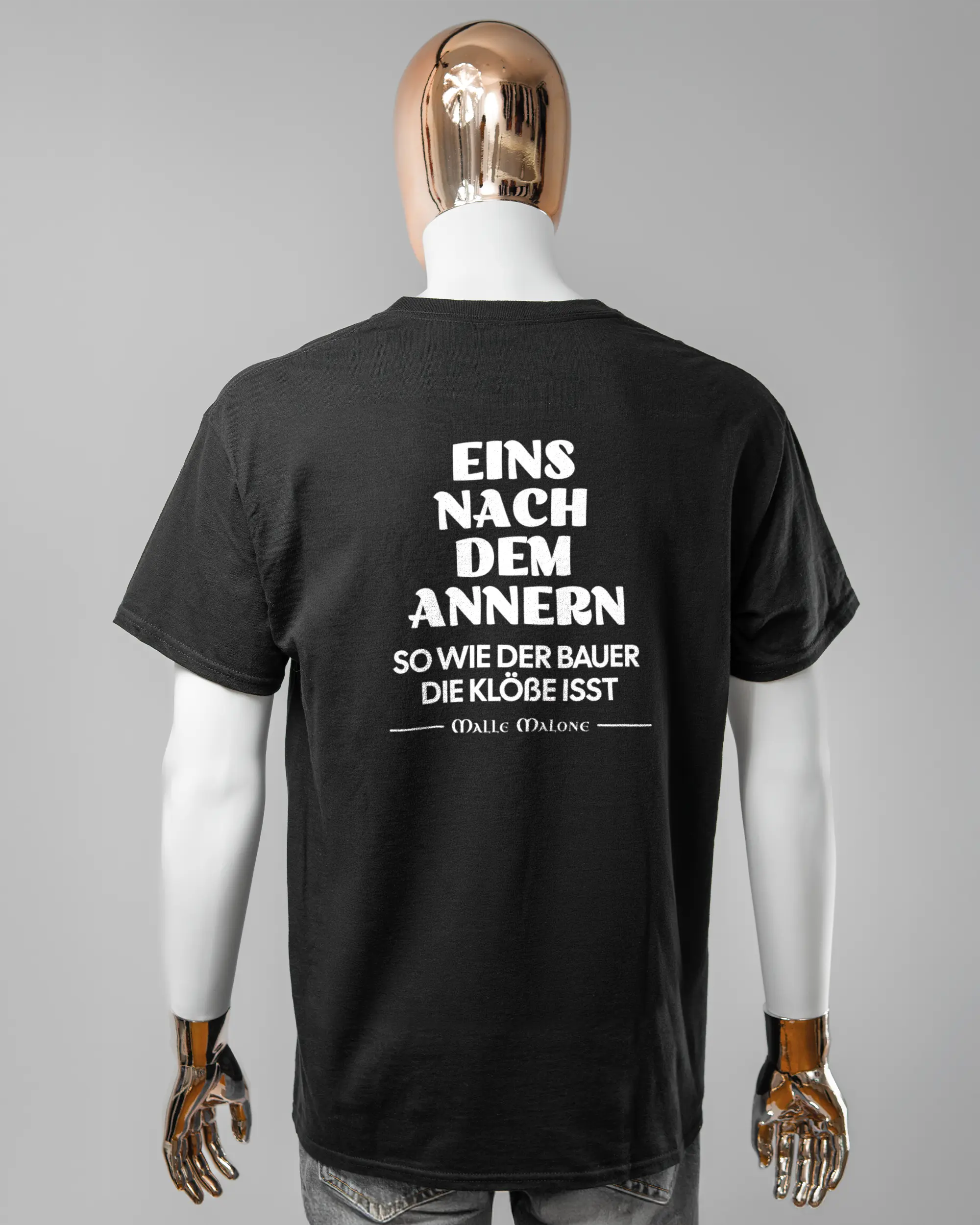 Rückseite des Basic Unisex T-Shirt Regular von Maondo mit dem Design Eins nach dem Annern in der Farbe Black und in der Größe L getragen von einer maskulinen Puppe