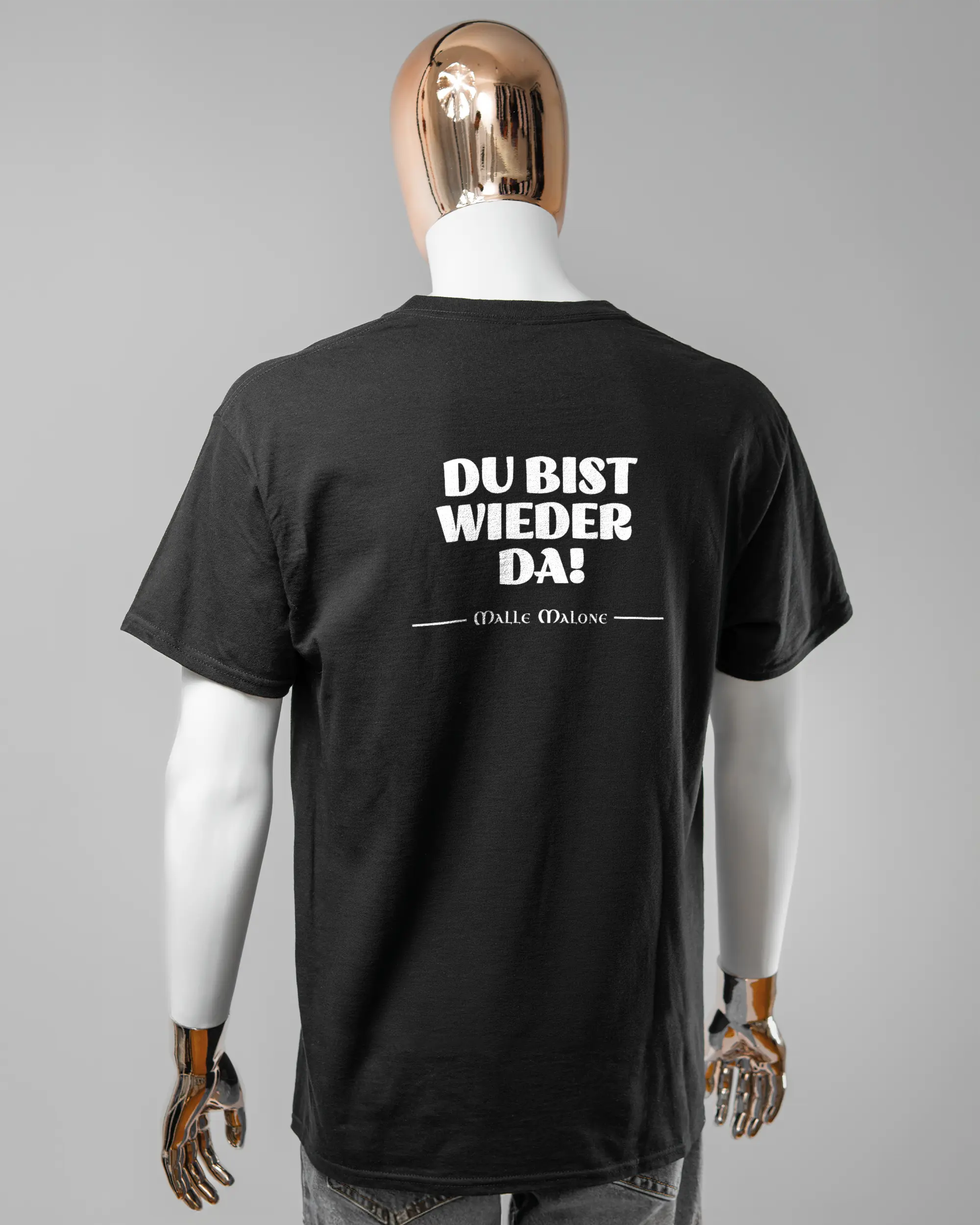 Rückseite des Basic Unisex T-Shirt Regular von Maondo mit dem Design Wieder da in der Farbe Black und in der Größe L getragen von einer maskulinen Puppe