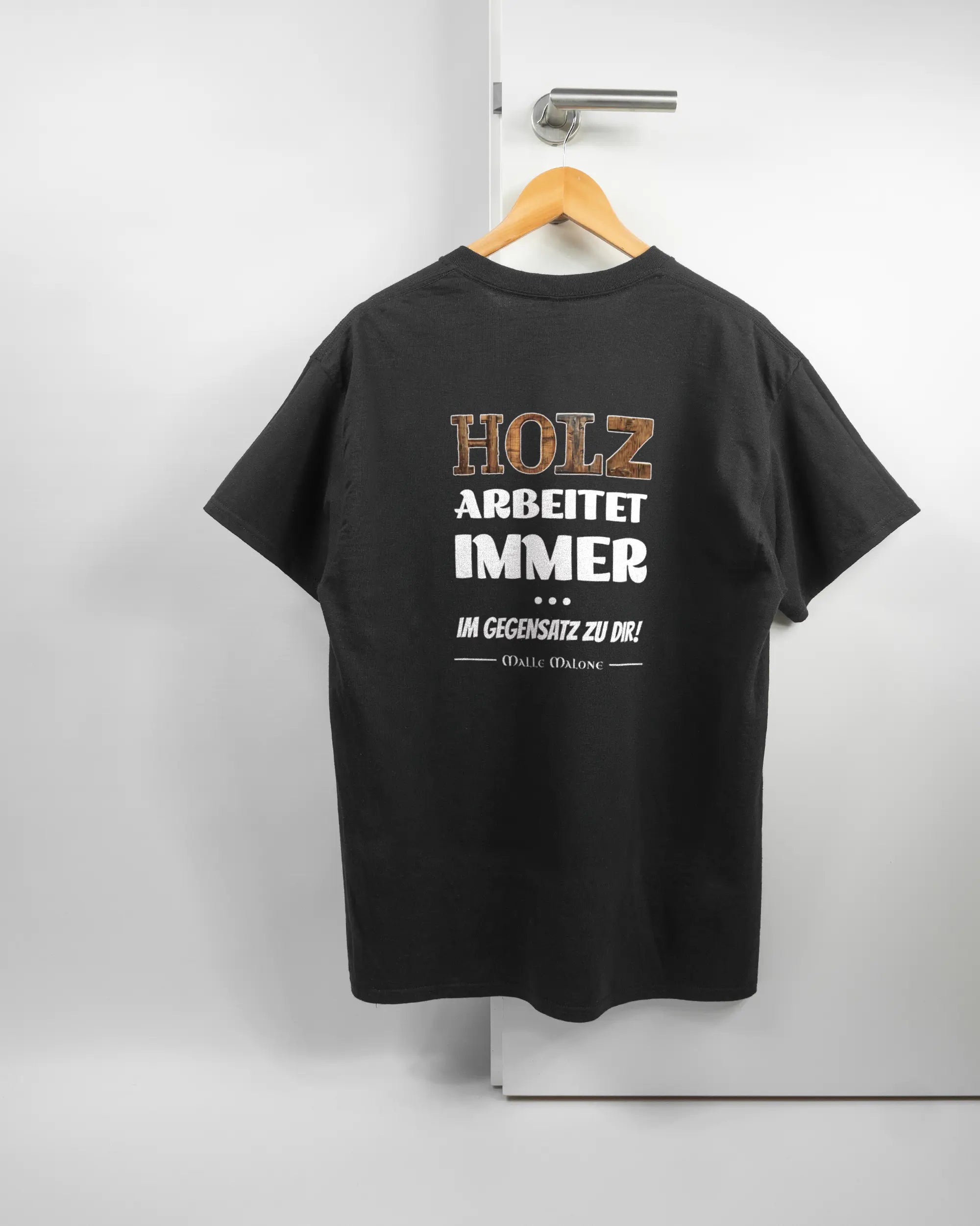 Rückseite des Basic Unisex T-Shirt Regular von Maondo mit dem Design Holzarbeit in der Farbe Black und in der Größe L auf einem Bügel an der Türklinke aufgehängt
