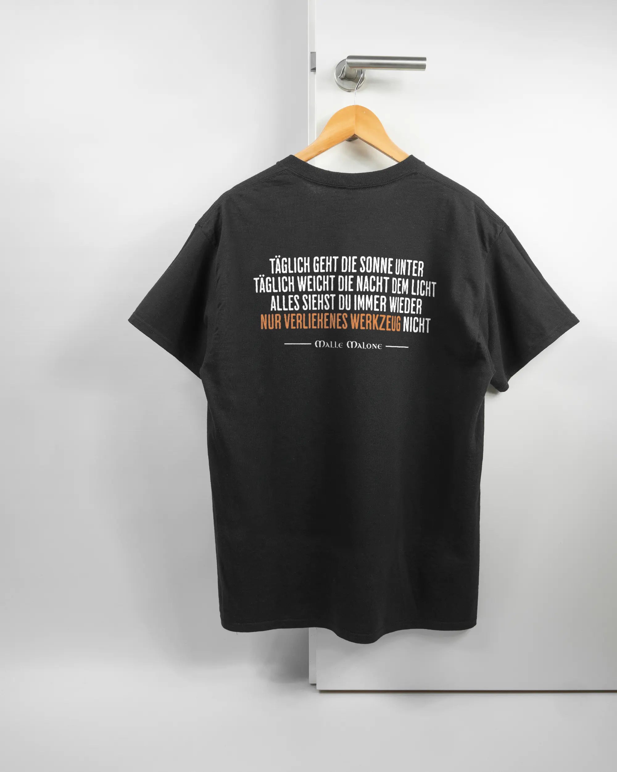 Rückseite des Basic Unisex T-Shirt Regular von Maondo mit dem Design Wegzeug in der Farbe Black und in der Größe L auf einem Bügel an der Türklinke aufgehängt
