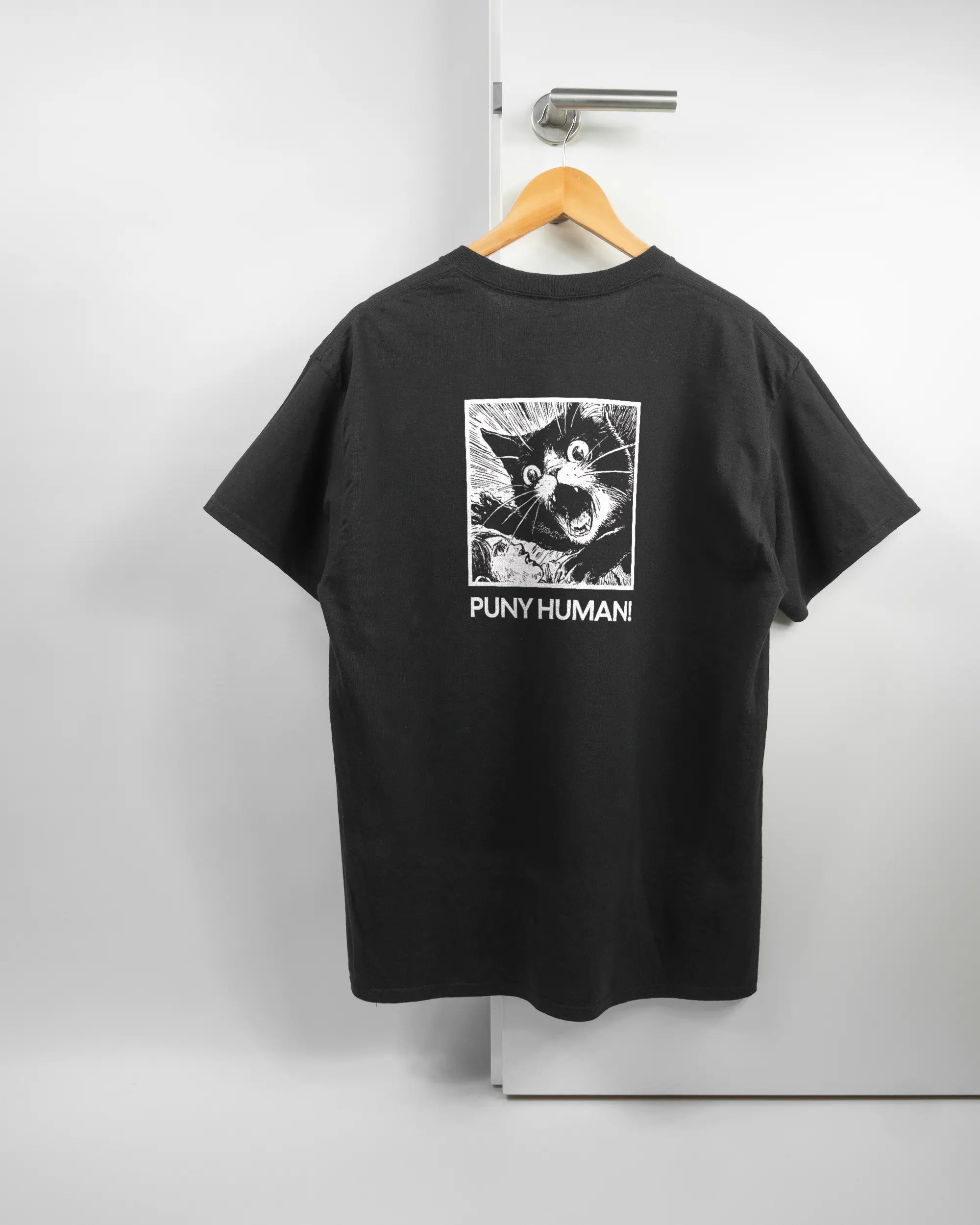 Rückseite des Basic Unisex T-Shirt Regular von Maondo mit dem Design Puny Human in der Farbe Black und in der Größe L auf einem Bügel an der Türklinke aufgehängt