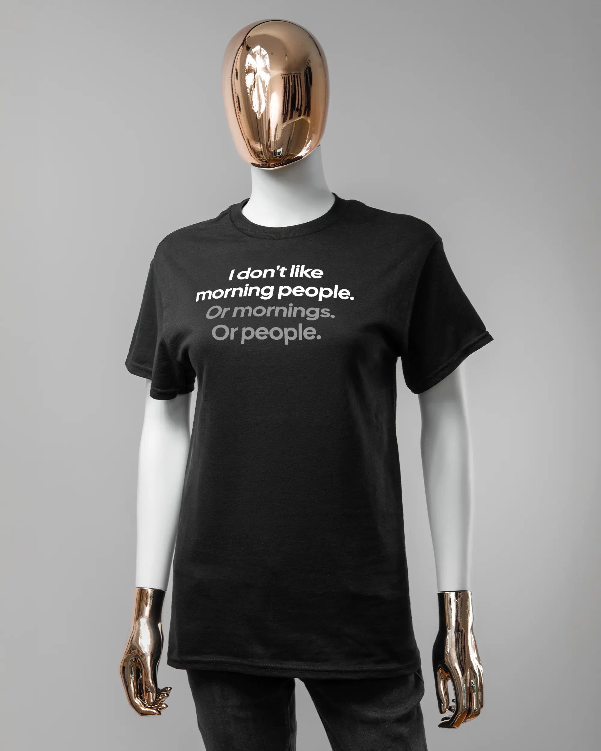 Vorderseite des Basic Unisex T-Shirt Regular von Maondo mit dem Design Morning Person in der Farbe Black und in der Größe S getragen von einer femininen Puppe