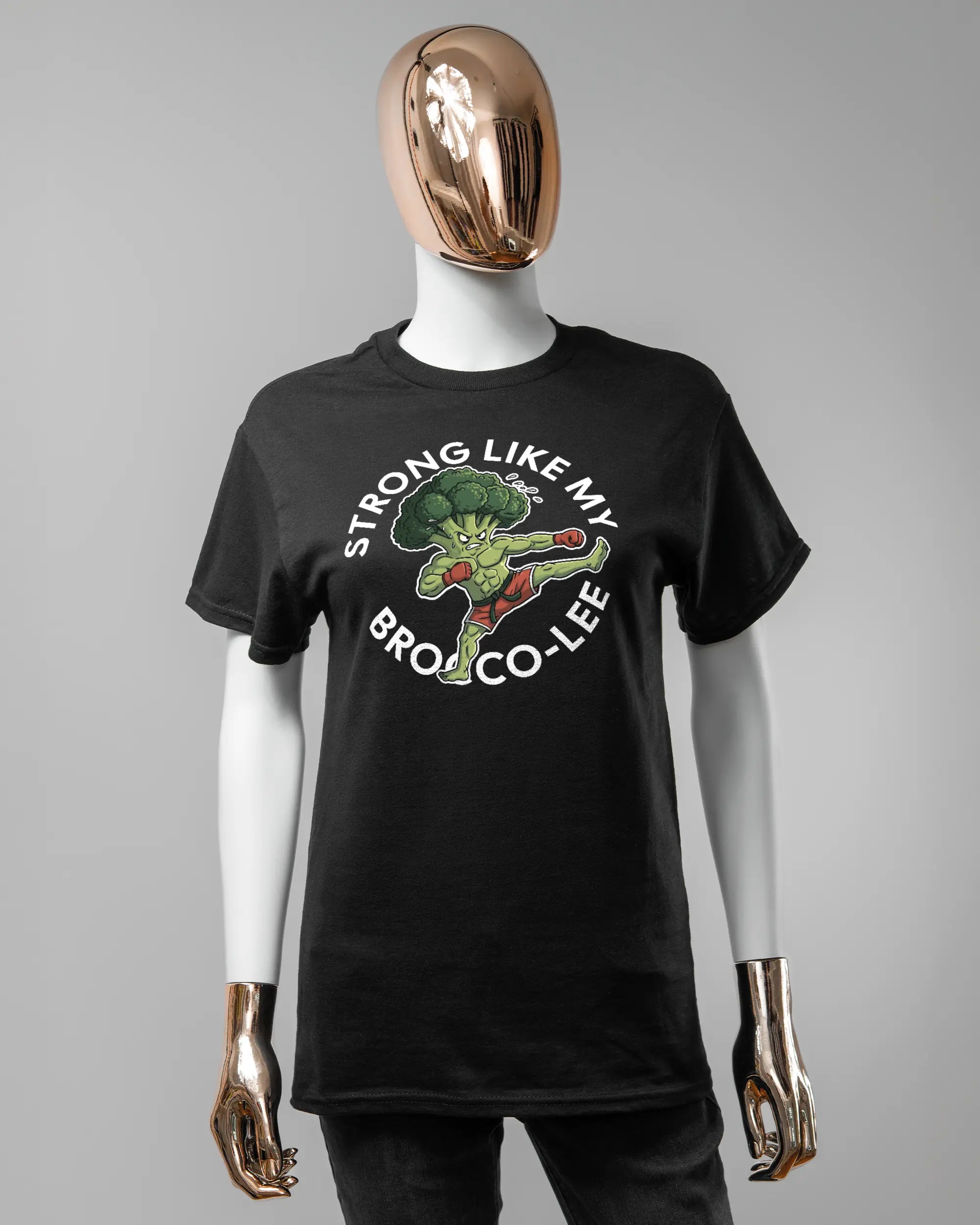 Vorderseite des Basic Unisex T-Shirt Regular von Maondo mit dem Design Brocco-Lee in der Farbe Black und in der Größe S getragen von einer femininen Puppe