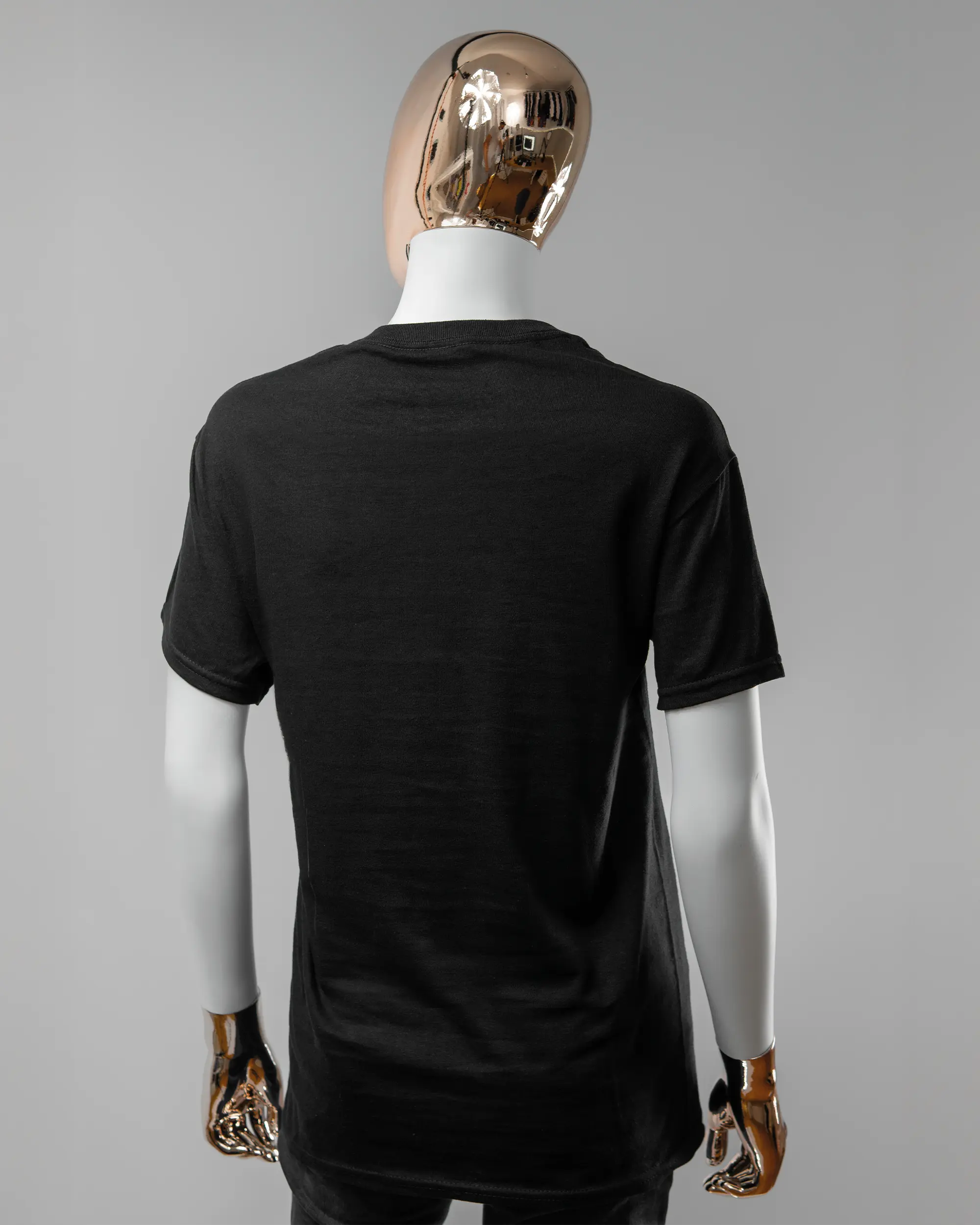 Rückseite des Basic Unisex T-Shirt Regular von Maondo ohne Motiv in der Farbe Black und in der Größe S getragen von einer femininen Puppe