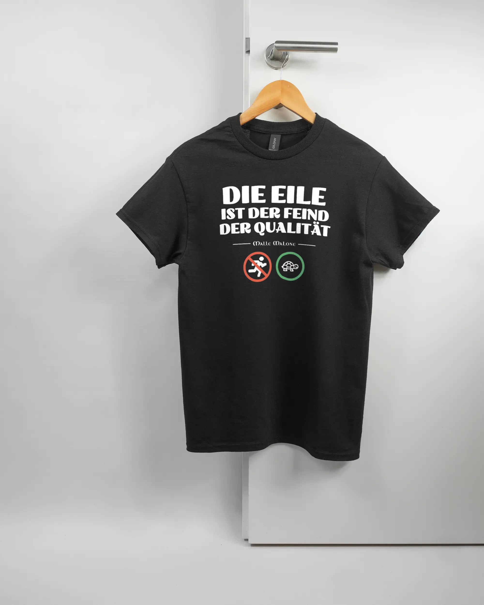 Vorderseite des Basic Unisex T-Shirt Regular von Maondo mit dem Design Keine Eile in der Farbe Black und in der Größe S auf einem Bügel an der Türklinke aufgehängt