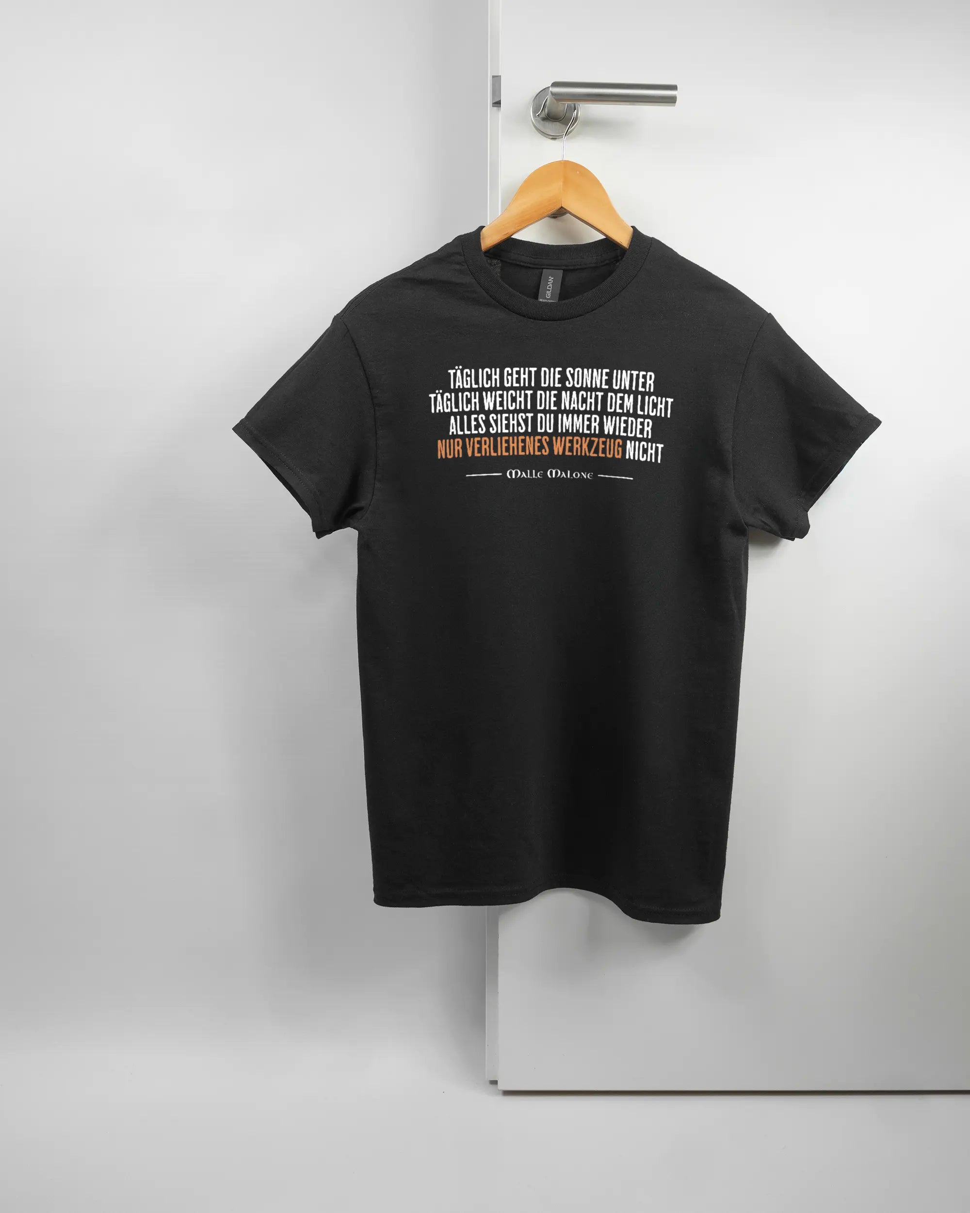 Vorderseite des Basic Unisex T-Shirt Regular von Maondo mit dem Design Wegzeug in der Farbe Black und in der Größe S auf einem Bügel an der Türklinke aufgehängt