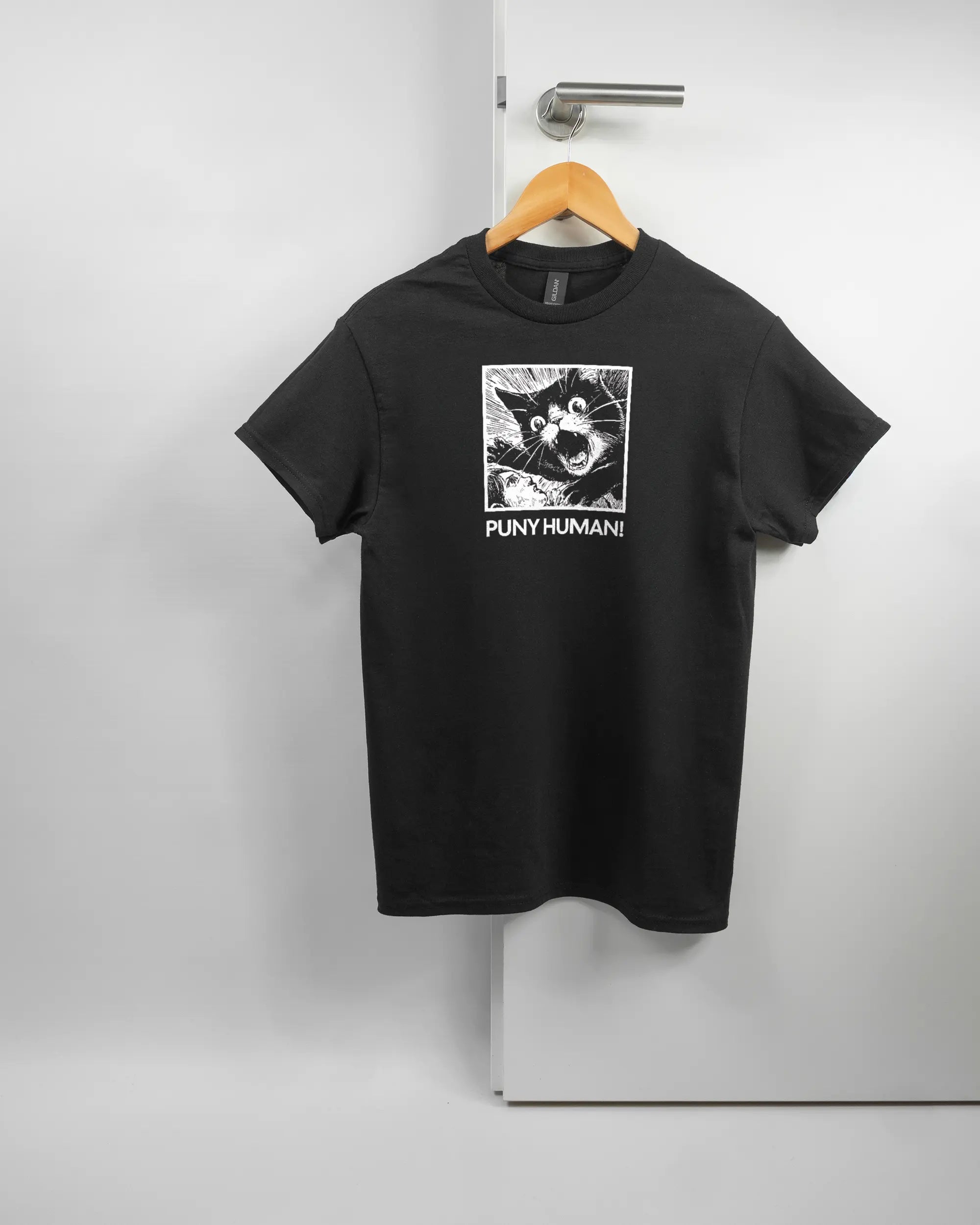 Vorderseite des Basic Unisex T-Shirt Regular von Maondo mit dem Design Puny Human in der Farbe Black und in der Größe S auf einem Bügel an der Türklinke aufgehängt