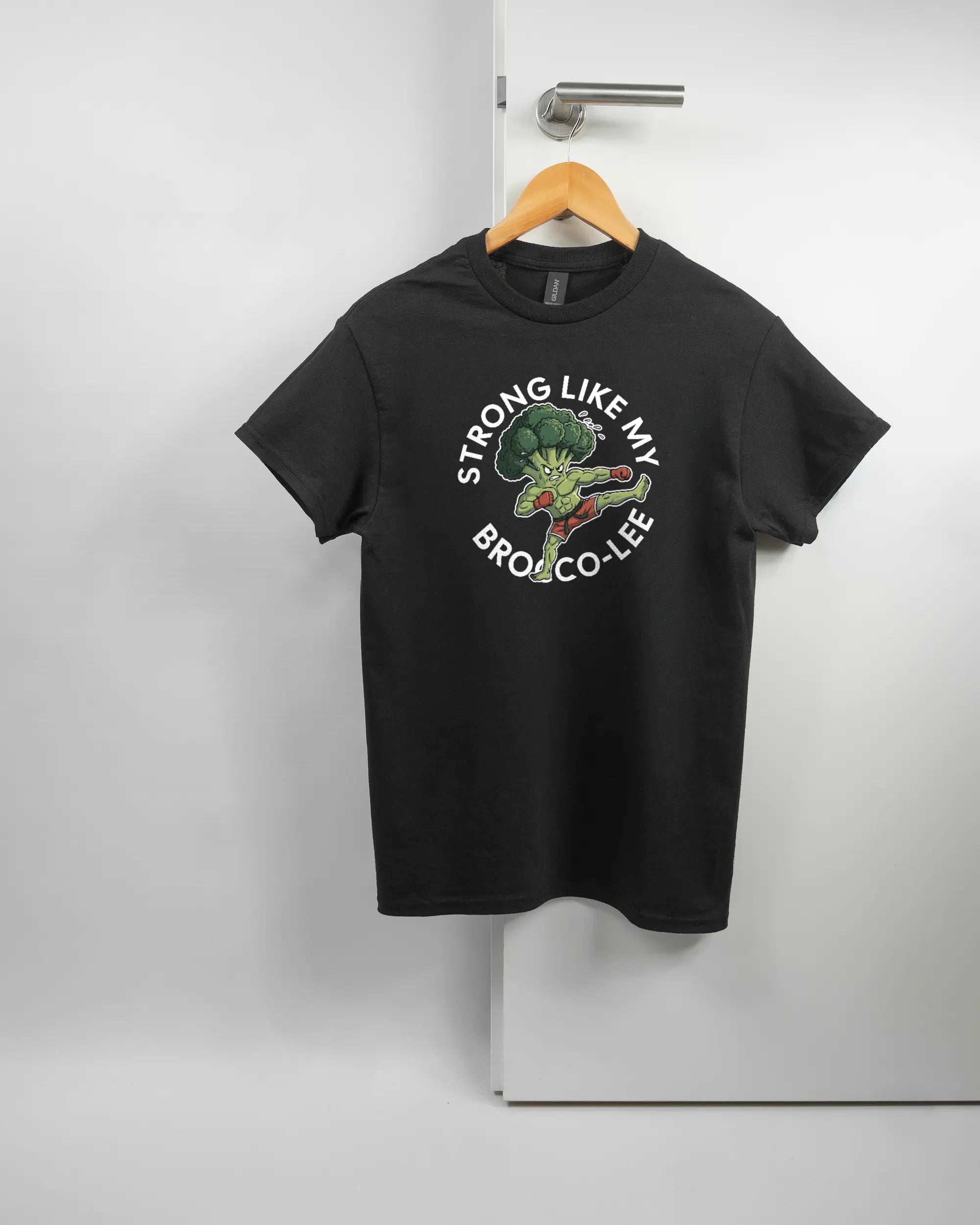 Vorderseite des Basic Unisex T-Shirt Regular von Maondo mit dem Design Brocco-Lee in der Farbe Black und in der Größe S auf einem Bügel an der Türklinke aufgehängt