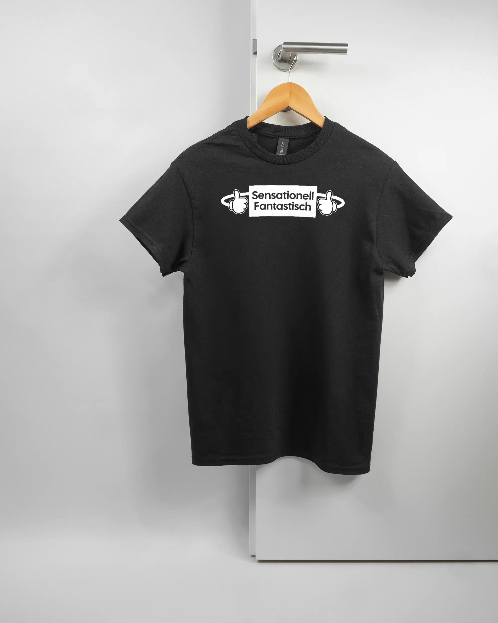 Vorderseite des Basic Unisex T-Shirt Regular von Maondo mit dem Design Fantastisch in der Farbe Black und in der Größe S auf einem Bügel an der Türklinke aufgehängt
