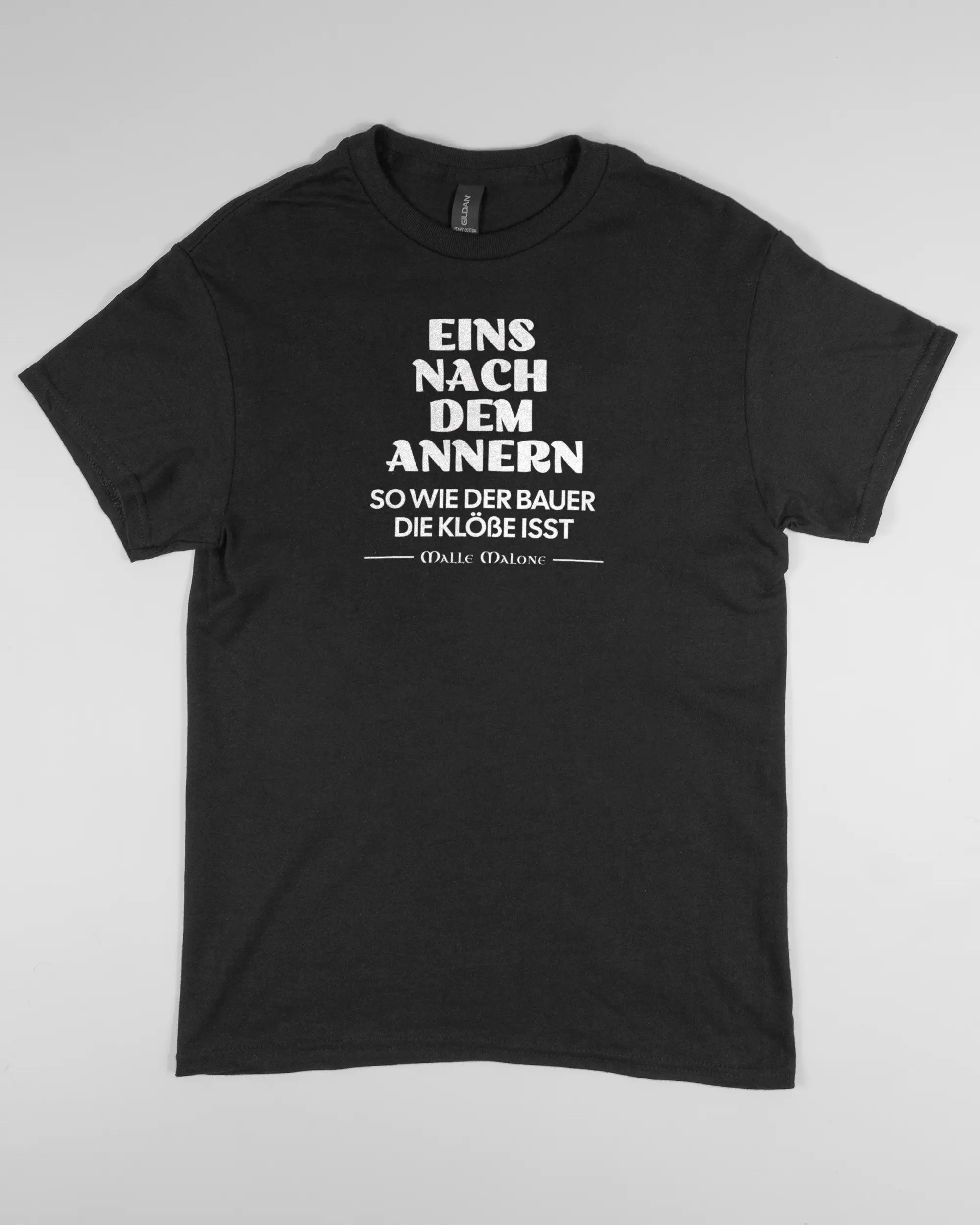 Vorderseite des Basic Unisex T-Shirt Regular von Maondo mit dem Design Eins nach dem Annern in der Farbe Black und in der Größe S flach auf den Boden gelegt