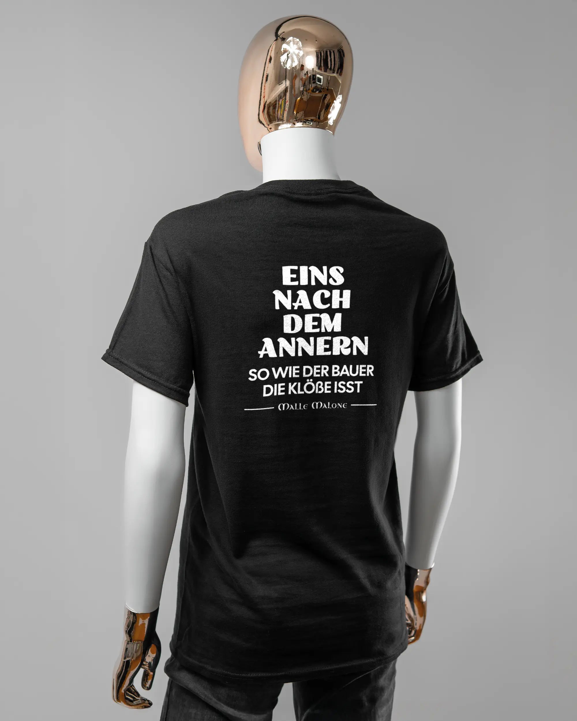 Rückseite des Basic Unisex T-Shirt Regular von Maondo mit dem Design Eins nach dem Annern in der Farbe Black und in der Größe S getragen von einer femininen Puppe