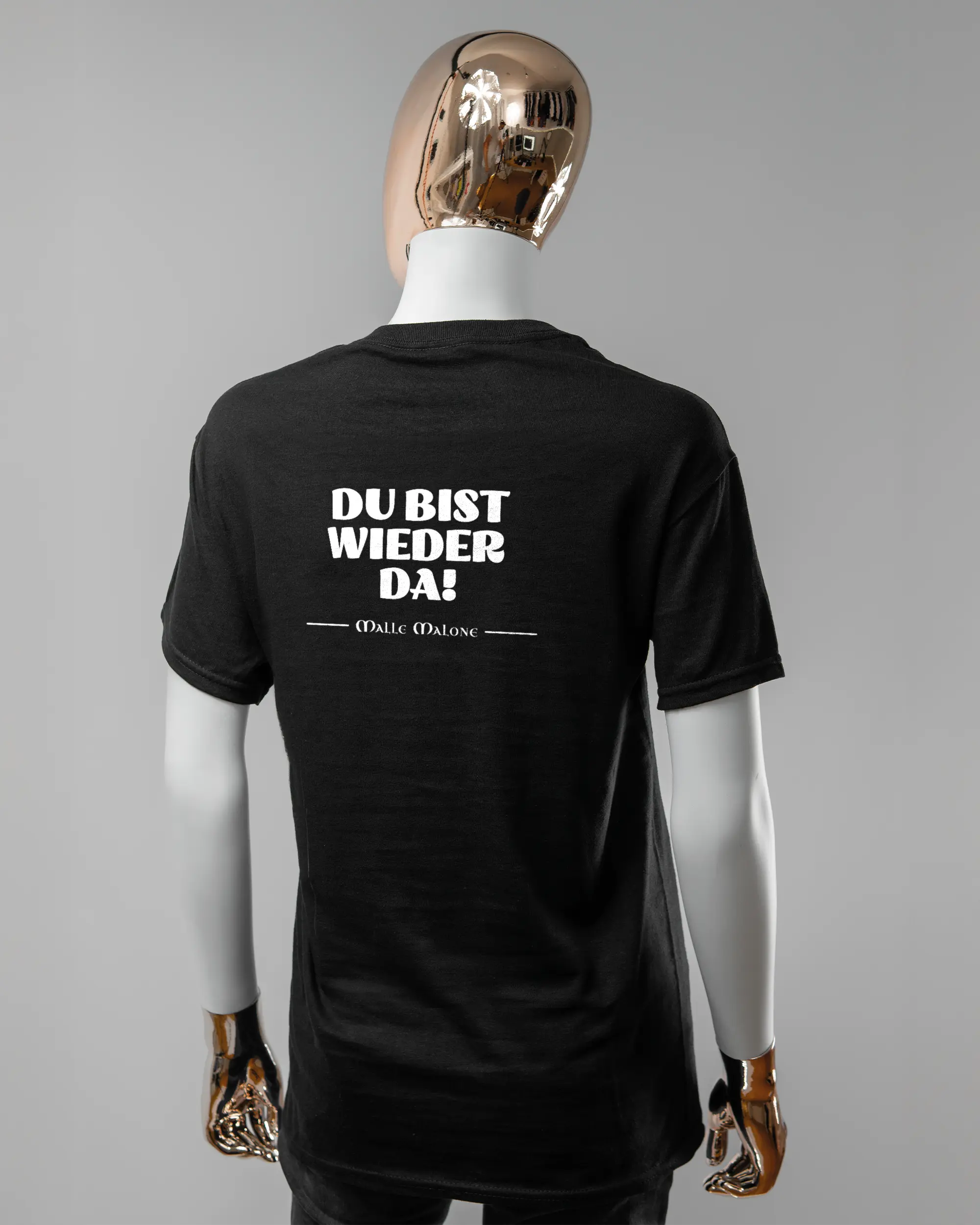 Rückseite des Basic Unisex T-Shirt Regular von Maondo mit dem Design Wieder da in der Farbe Black und in der Größe S getragen von einer femininen Puppe