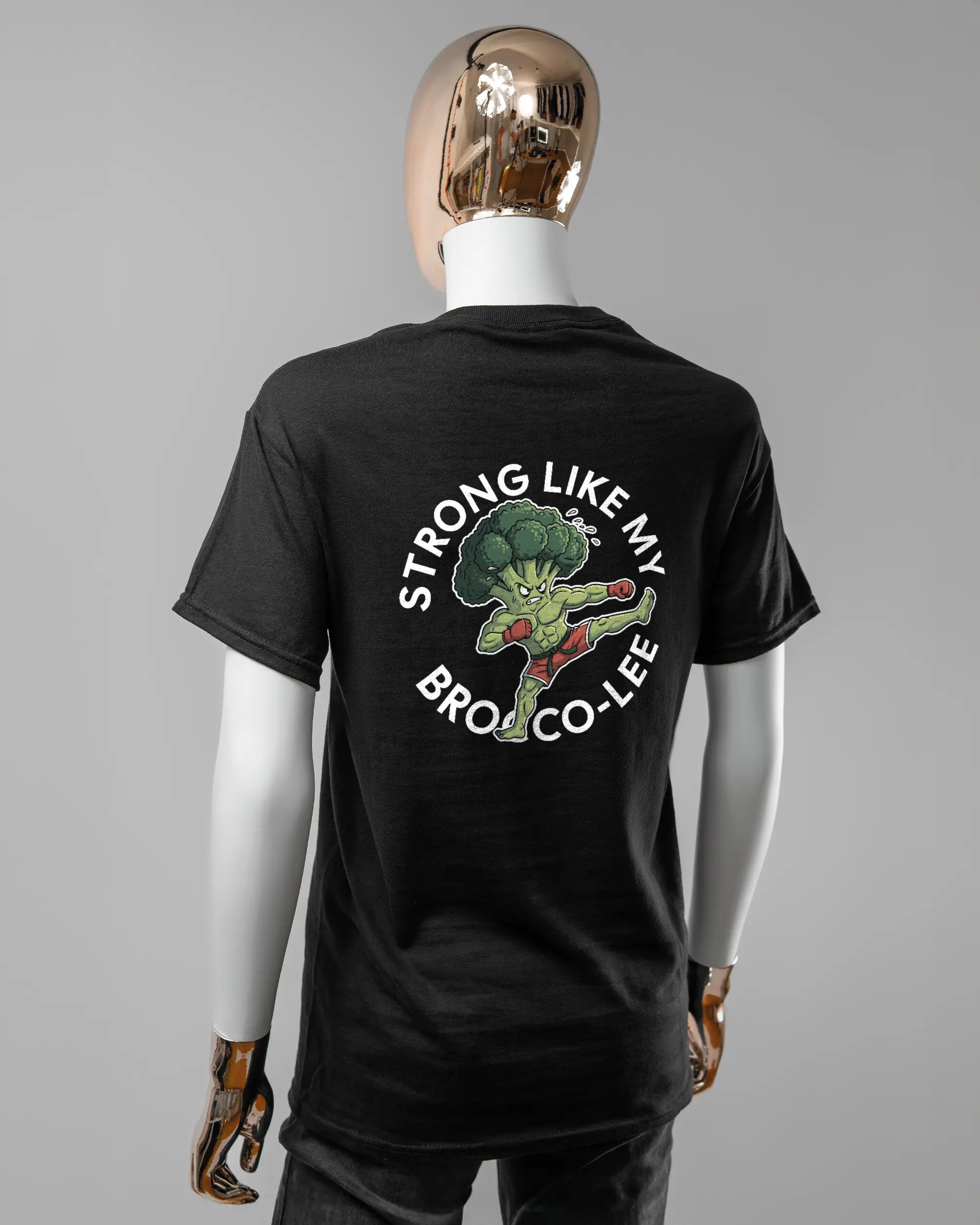 Rückseite des Basic Unisex T-Shirt Regular von Maondo mit dem Design Brocco-Lee in der Farbe Black und in der Größe S getragen von einer femininen Puppe