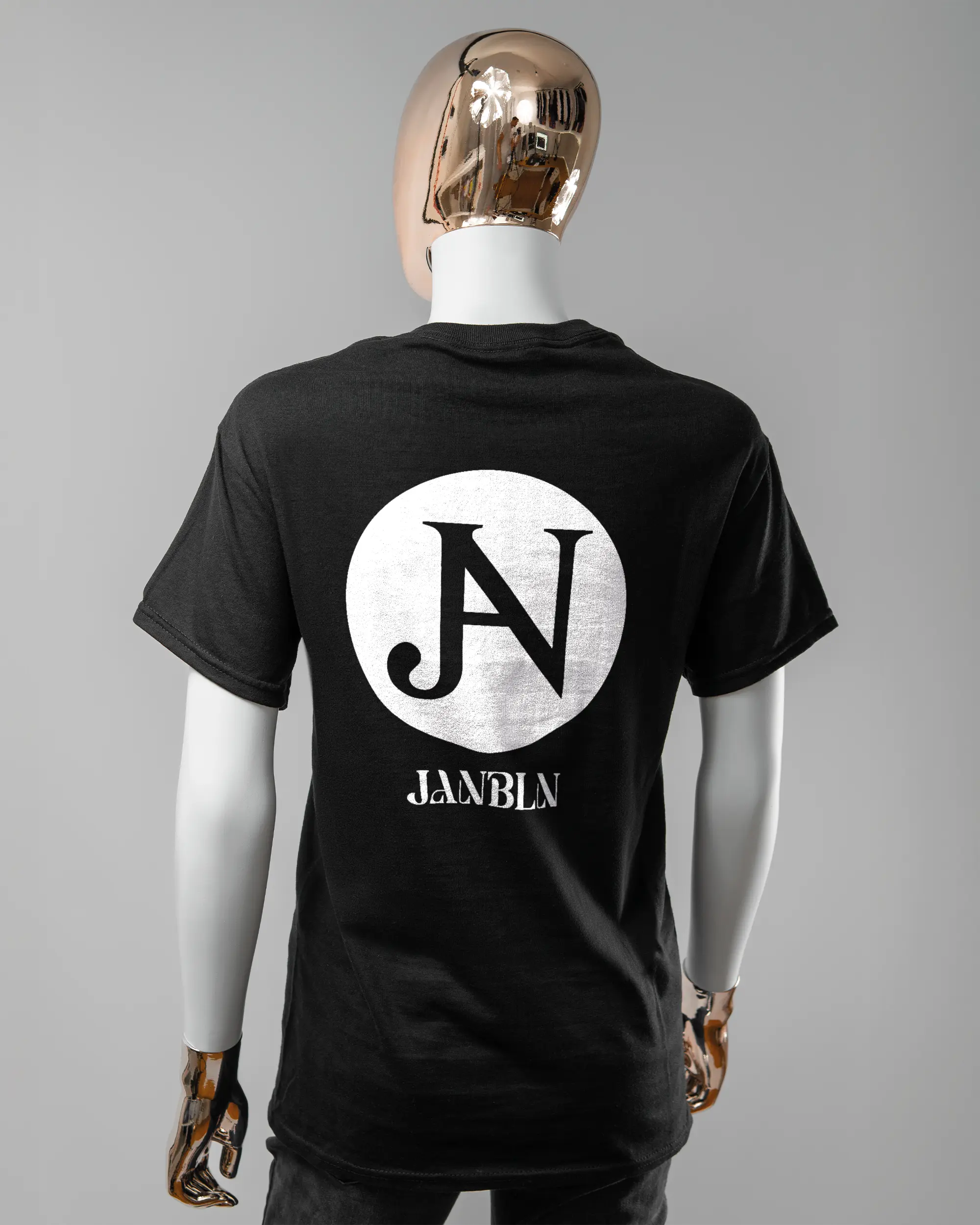 Rückseite des Basic Unisex T-Shirt Regular von Maondo mit dem Design JB1 in der Farbe Black und in der Größe S getragen von einer femininen Puppe