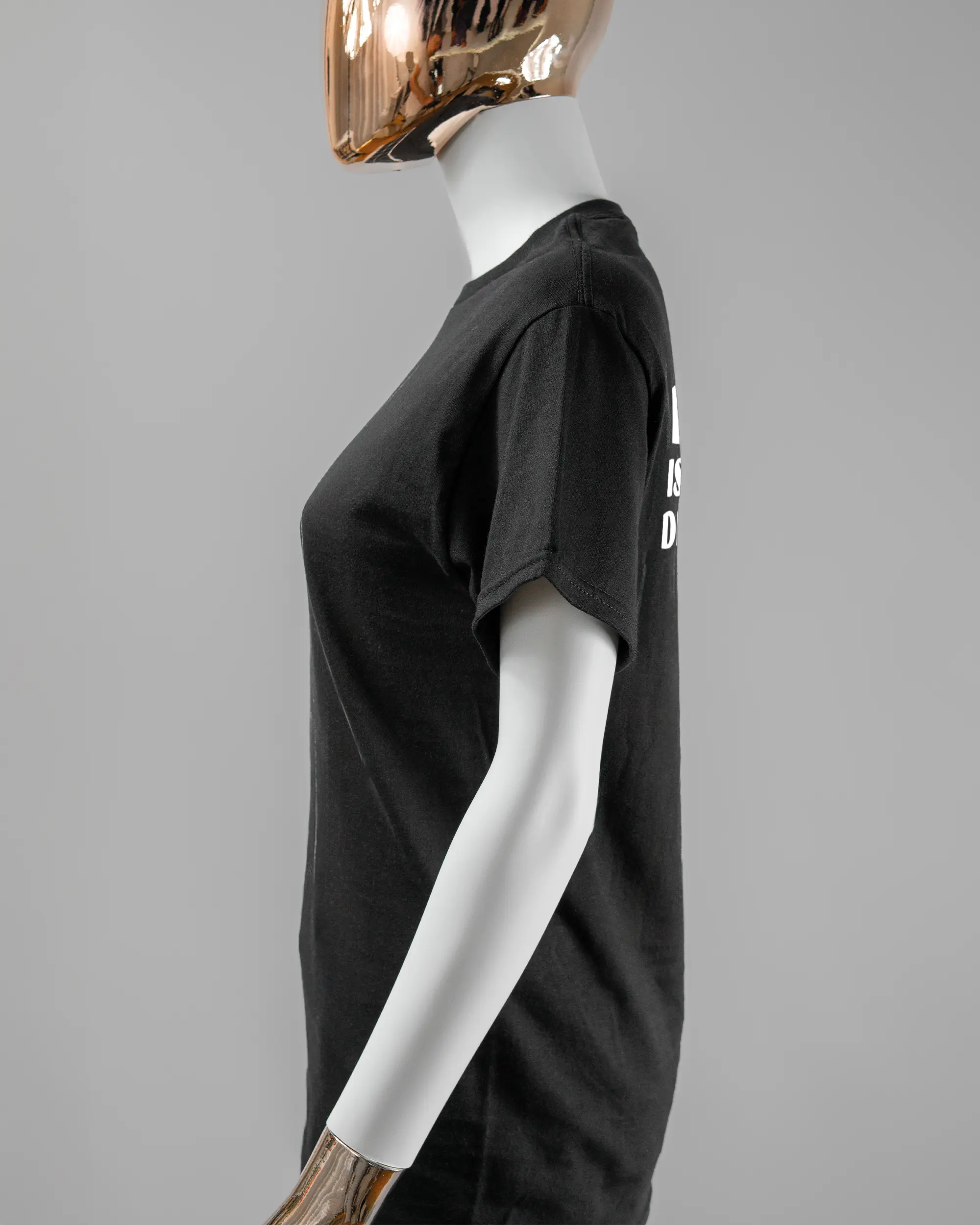 Seitenansicht des Basic Unisex T-Shirt Regular von Maondo mit dem Design Keine Eile hinten in der Farbe Black und in der Größe S getragen von einer femininen Puppe