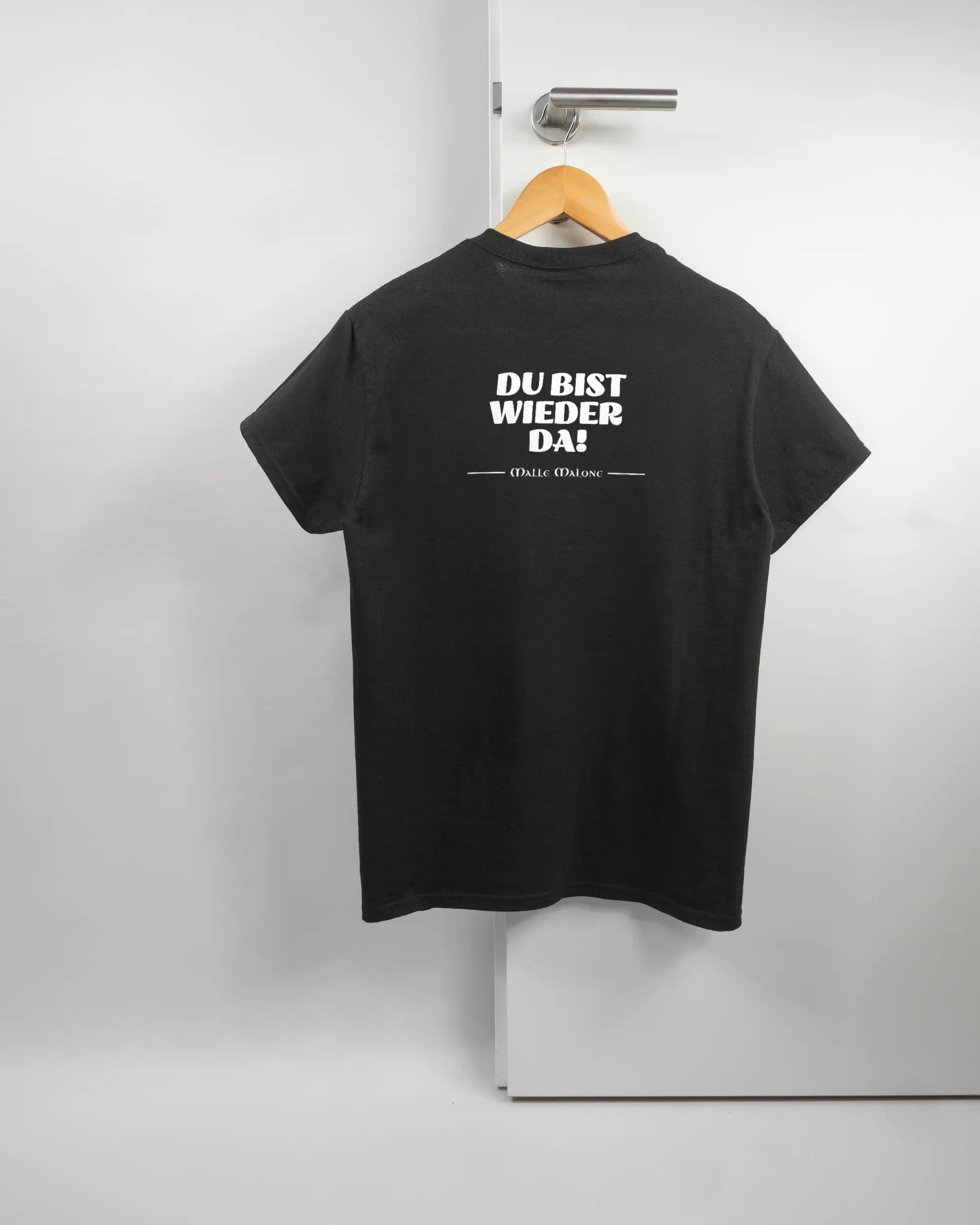 Rückseite des Basic Unisex T-Shirt Regular von Maondo mit dem Design Wieder da in der Farbe Black und in der Größe S auf einem Bügel an der Türklinke aufgehängt