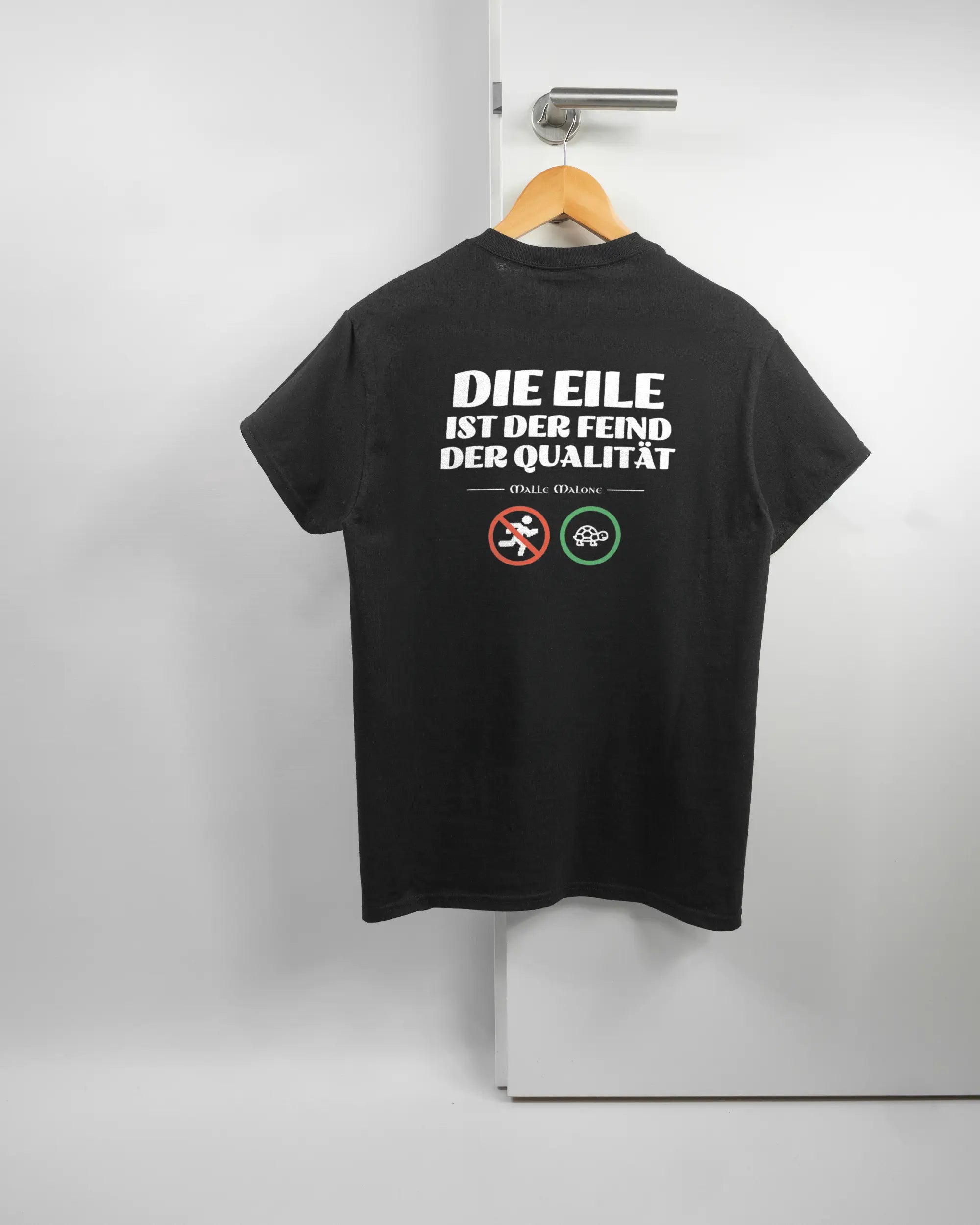 Rückseite des Basic Unisex T-Shirt Regular von Maondo mit dem Design Keine Eile in der Farbe Black und in der Größe S auf einem Bügel an der Türklinke aufgehängt