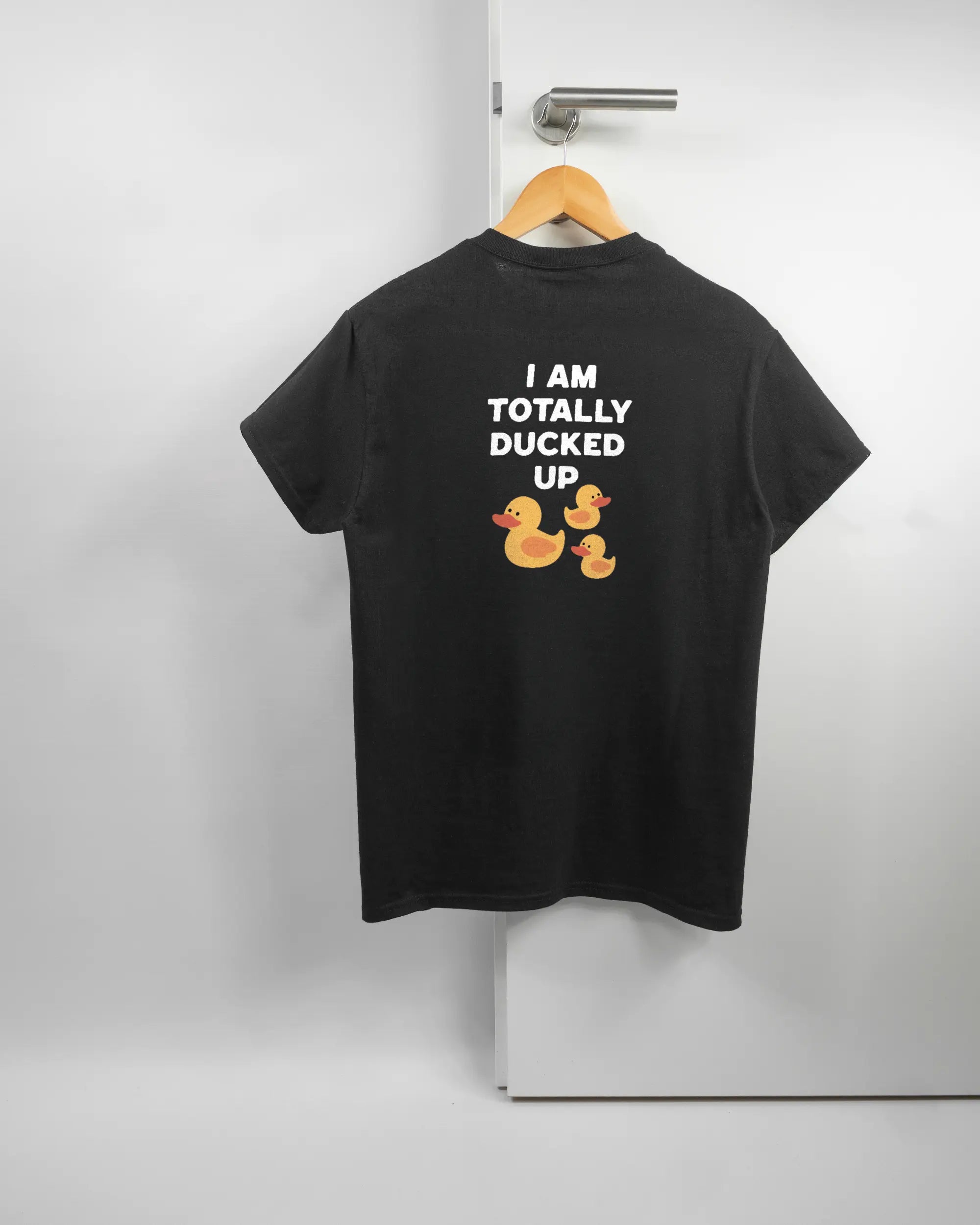 Rückseite des Basic Unisex T-Shirt Regular von Maondo mit dem Design Ducked Up in der Farbe Black und in der Größe S auf einem Bügel an der Türklinke aufgehängt