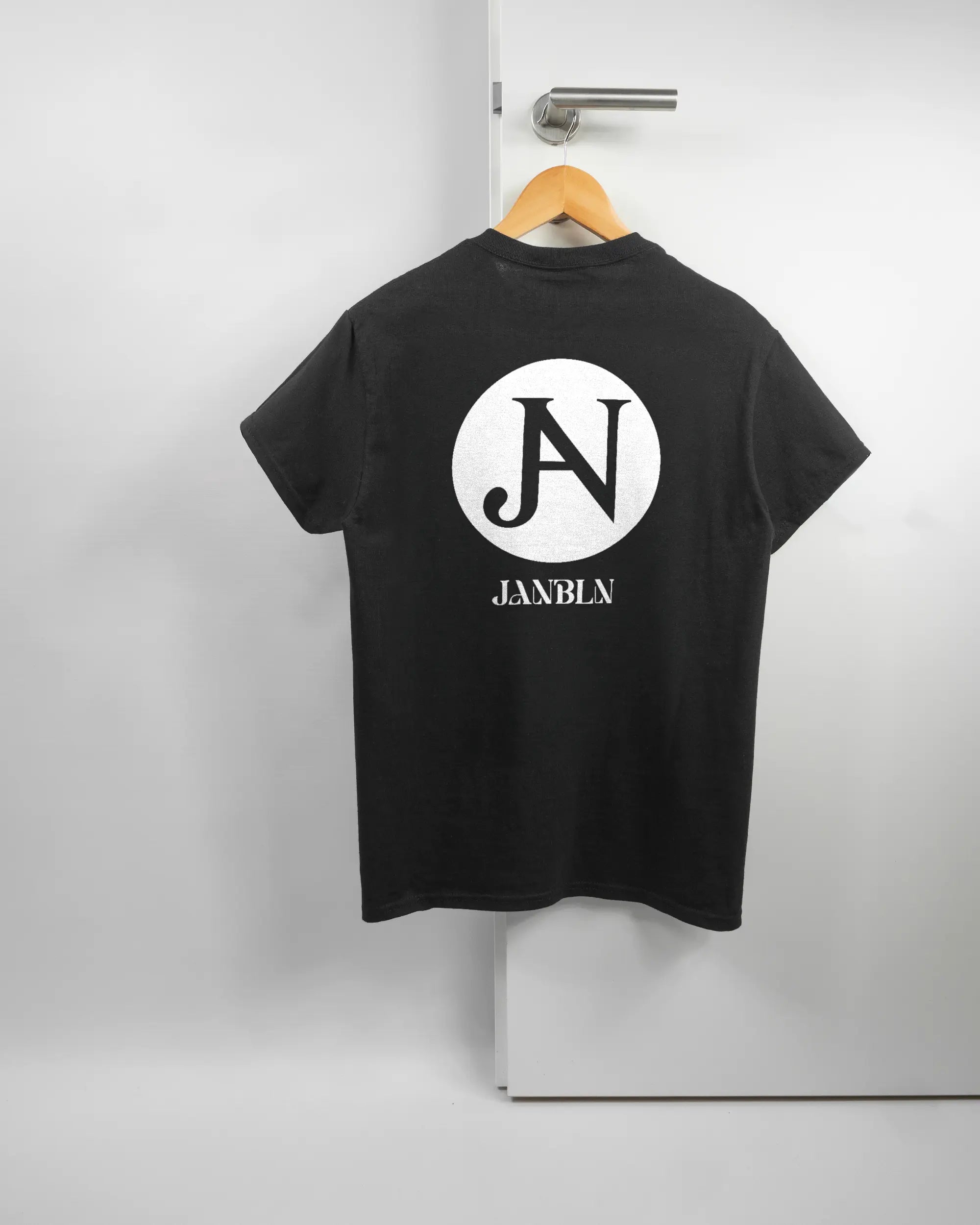 Rückseite des Basic Unisex T-Shirt Regular von Maondo mit dem Design JB1 in der Farbe Black und in der Größe S auf einem Bügel an der Türklinke aufgehängt