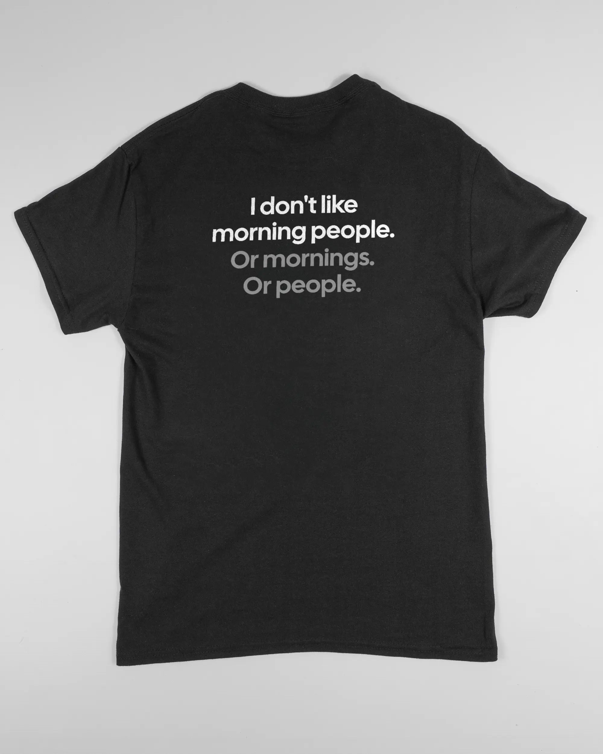 Rückseite des Basic Unisex T-Shirt Regular von Maondo mit dem Design Morning Person in der Farbe Black und in der Größe S flach auf den Boden gelegt