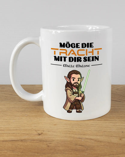 Titelbild, das die linke Seite der beidseitig bedruckten Keramiktasse von Maondo mit dem Design Tracht mit dir in der Farbe White auf einem Holztisch zeigt