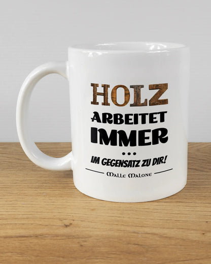 Titelbild, das die linke Seite der beidseitig bedruckten Keramiktasse von Maondo mit dem Design Holzarbeit in der Farbe White auf einem Holztisch zeigt