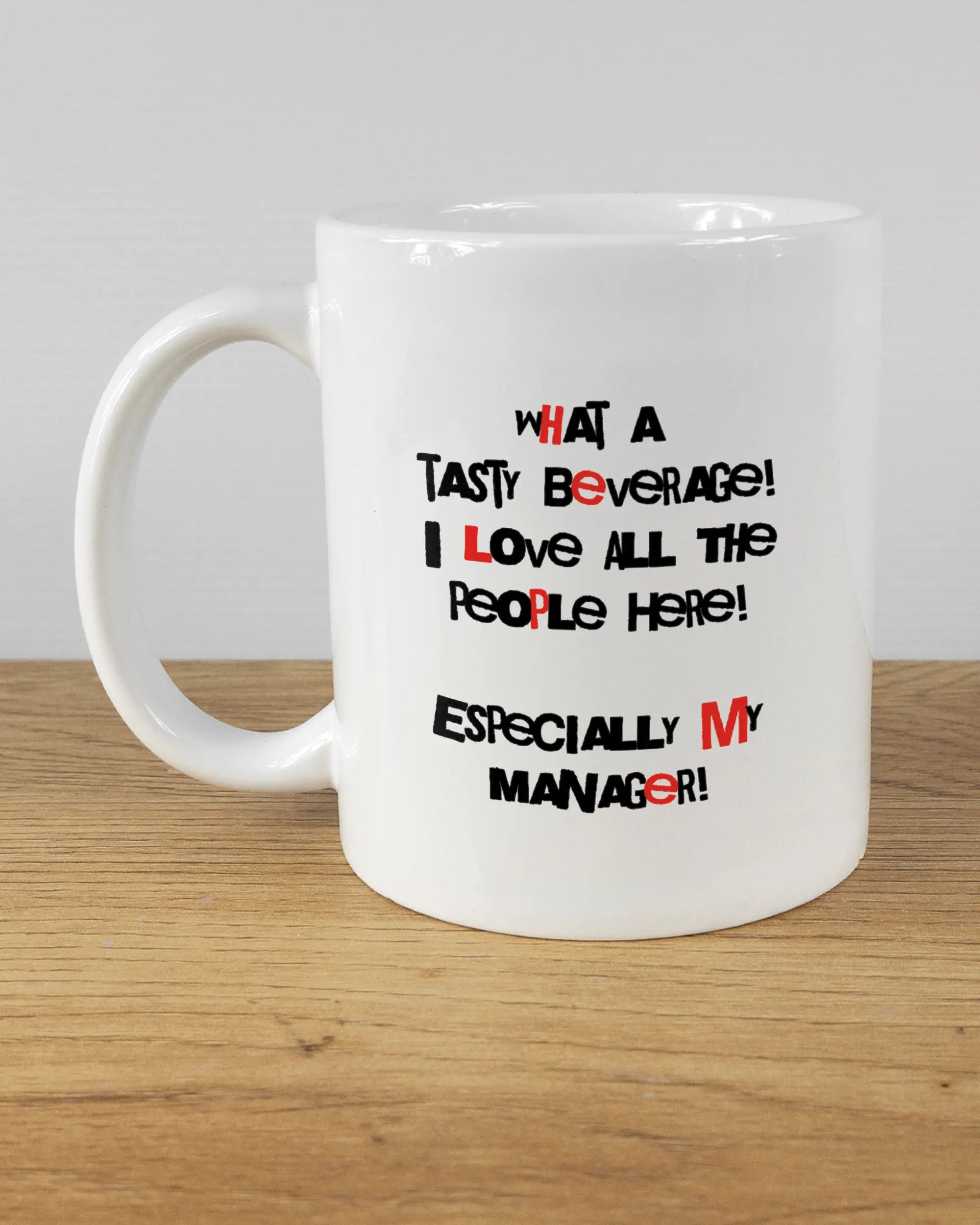 Titelbild, das die linke Seite der beidseitig bedruckten Keramiktasse von Maondo mit dem Design Help me in der Farbe White auf einem Holztisch zeigt