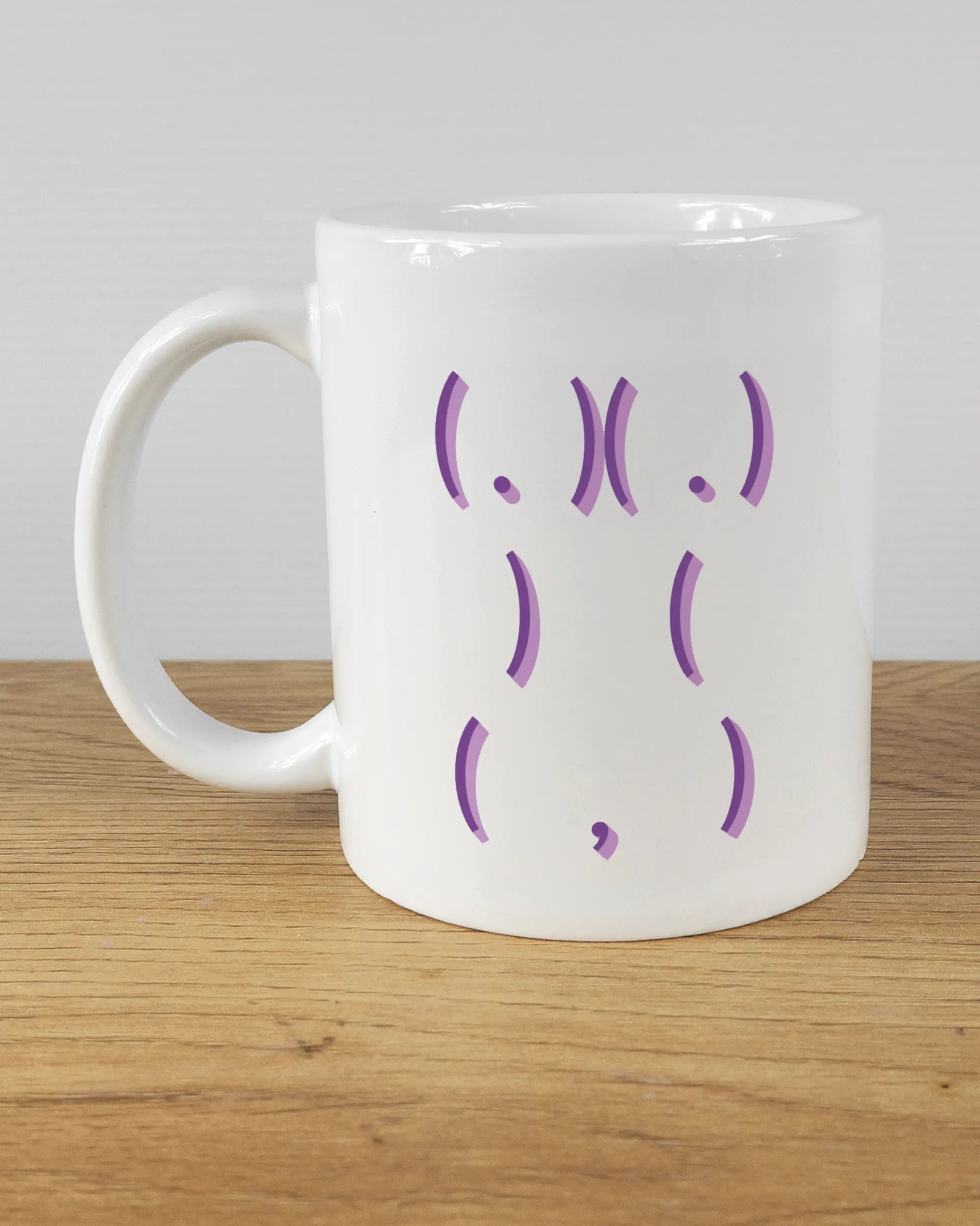 Titelbild, das die linke Seite der beidseitig bedruckten Keramiktasse von Maondo mit dem Design Body Language in der Farbe White auf einem Holztisch zeigt