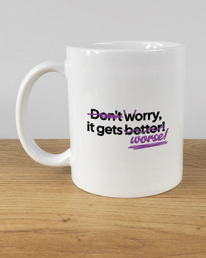 Titelbild, das die linke Seite der beidseitig bedruckten Keramiktasse von Maondo mit dem Design Worry Worse in der Farbe White auf einem Holztisch zeigt