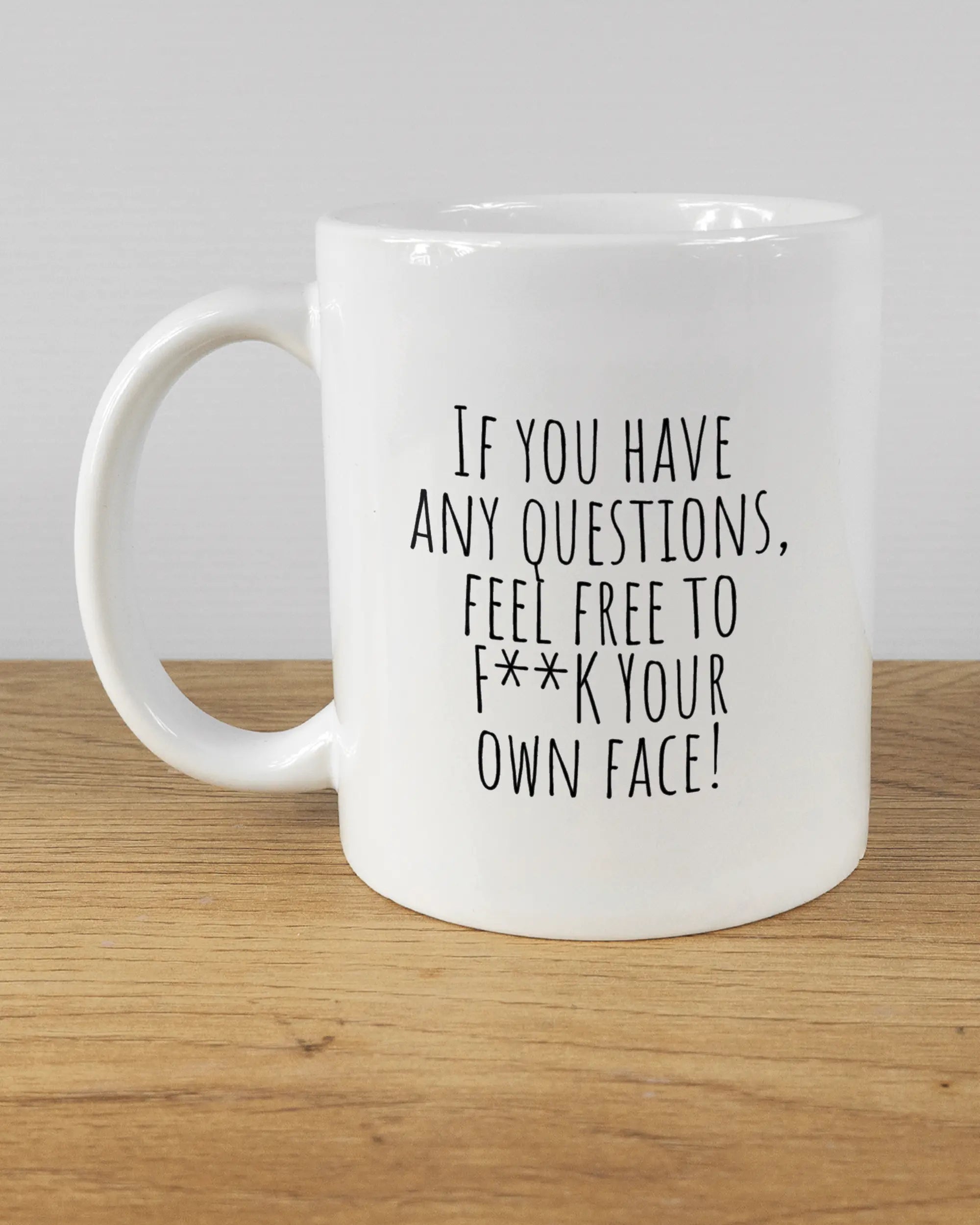 Titelbild, das die linke Seite der beidseitig bedruckten Keramiktasse von Maondo mit dem Design Feel Free in der Farbe White auf einem Holztisch zeigt