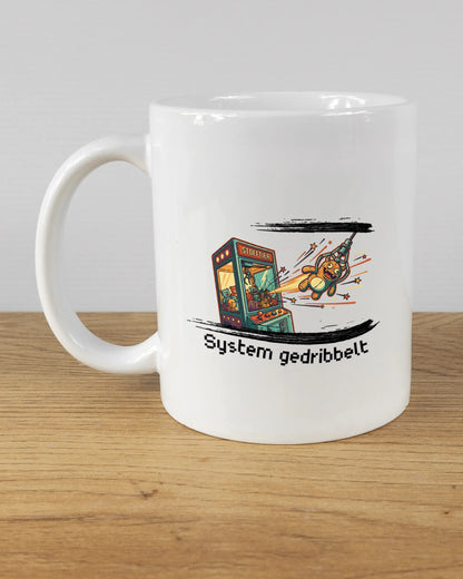 Titelbild, das die linke Seite der beidseitig bedruckten Keramiktasse von Maondo mit dem Design System gedribbelt in der Farbe White auf einem Holztisch zeigt