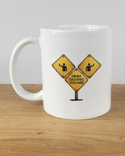 Titelbild, das die linke Seite der beidseitig bedruckten Keramiktasse von Maondo mit dem Design Schutzschild in der Farbe White auf einem Holztisch zeigt