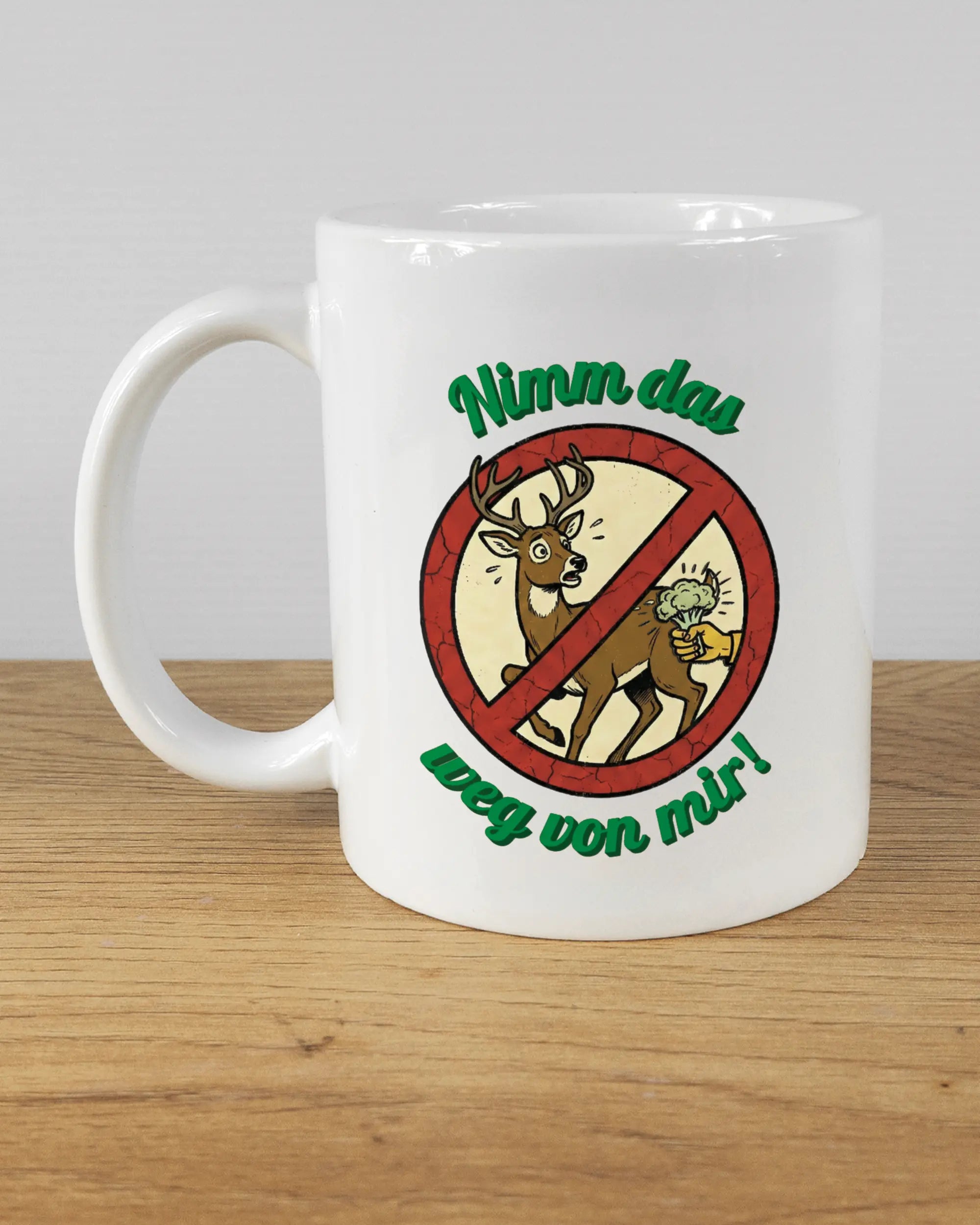 Titelbild, das die linke Seite der beidseitig bedruckten Keramiktasse von Maondo mit dem Design Reh weg in der Farbe White auf einem Holztisch zeigt