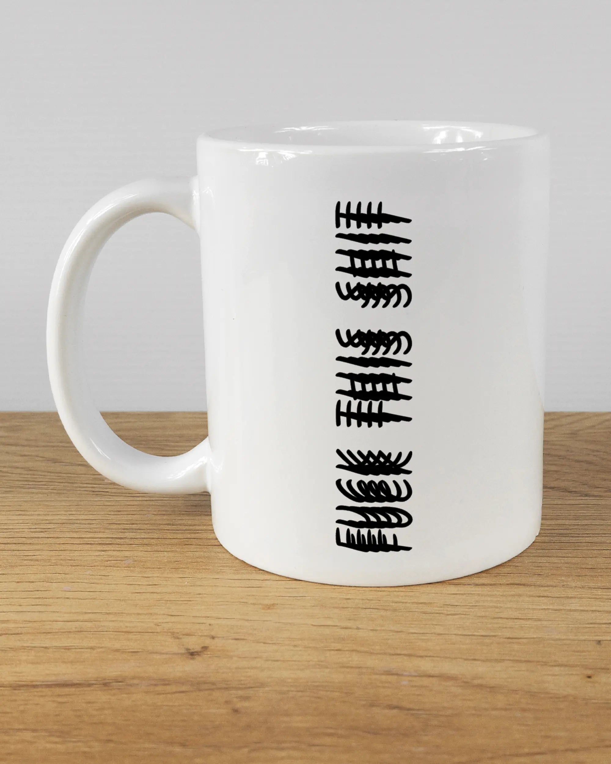 Titelbild, das die linke Seite der beidseitig bedruckten Keramiktasse von Maondo mit dem Design Hidden Message in der Farbe White auf einem Holztisch zeigt