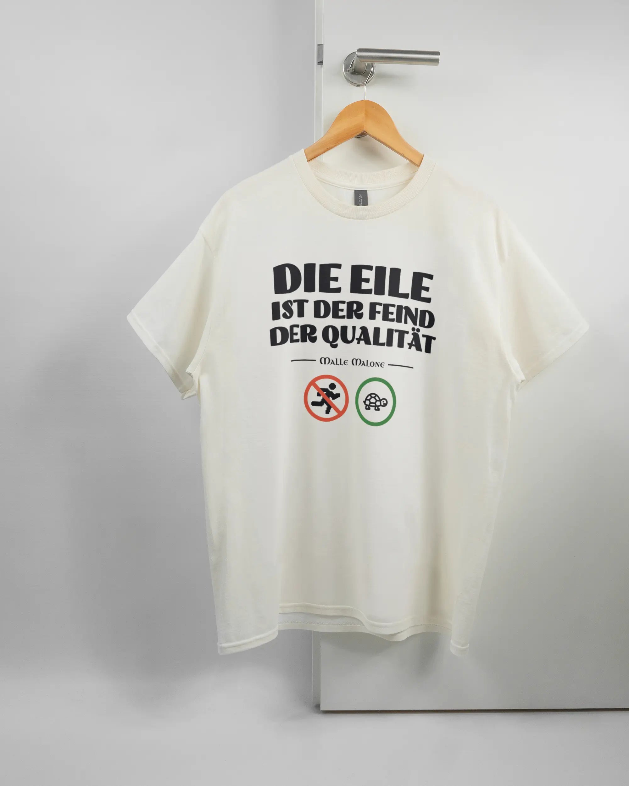 Vorderseite des Basic Unisex T-Shirt Regular von Maondo mit dem Design Keine Eile in der Farbe White und in der Größe L auf einem Bügel an der Türklinke aufgehängt