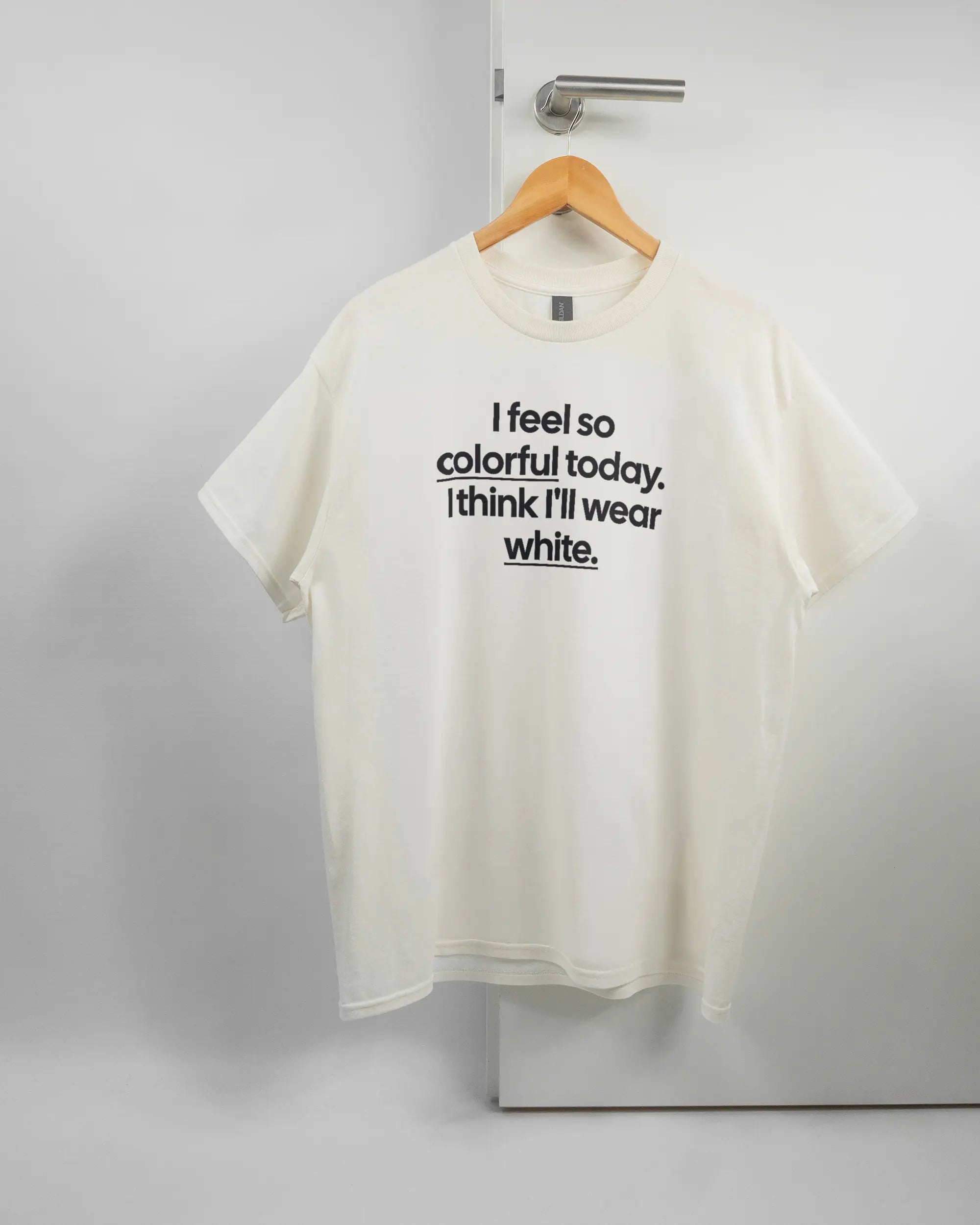 Vorderseite des Basic Unisex T-Shirt Regular von Maondo mit dem Design Colorful Day in der Farbe White und in der Größe L auf einem Bügel an der Türklinke aufgehängt
