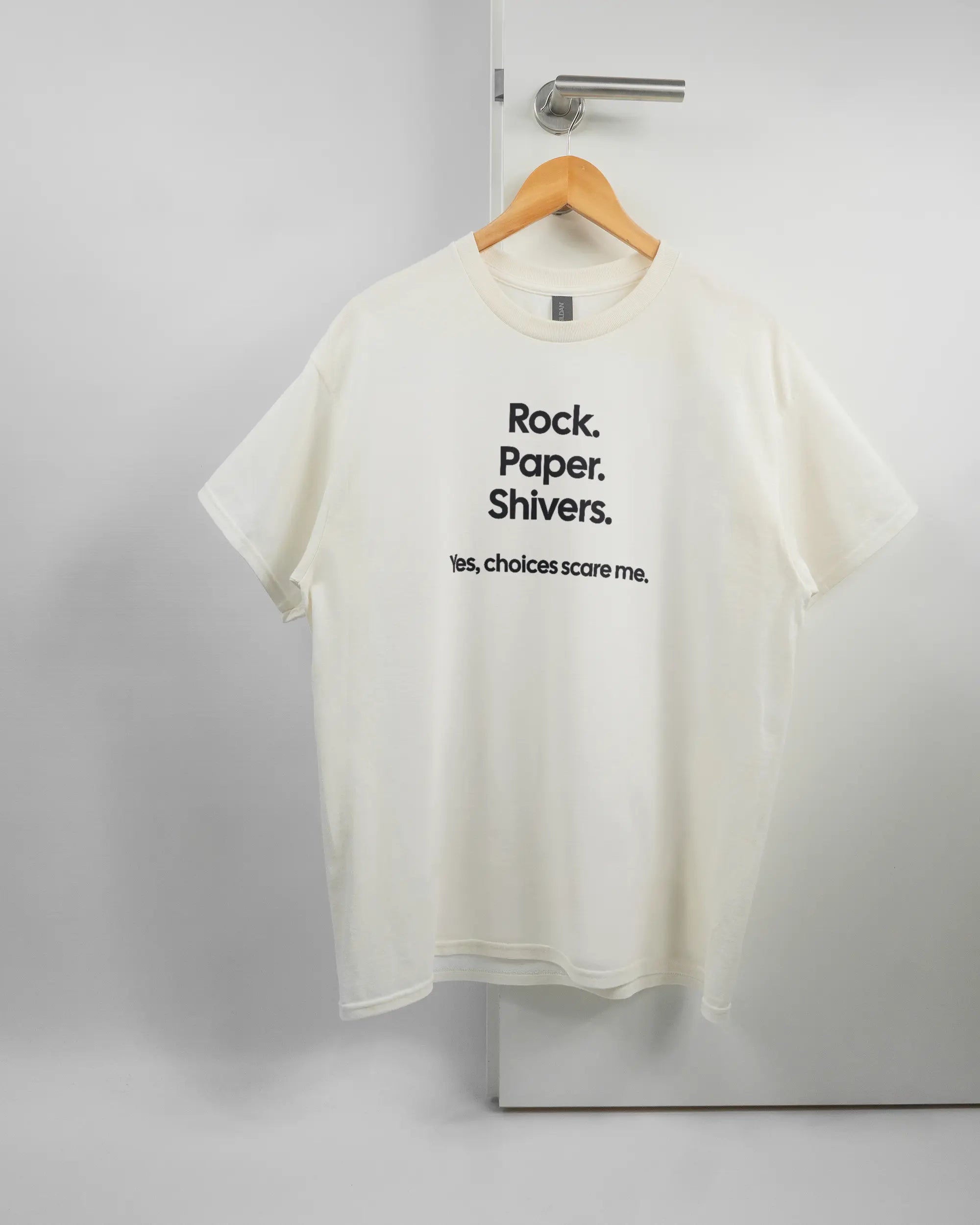 Vorderseite des Basic Unisex T-Shirt Regular von Maondo mit dem Design Rock Paper Shivers in der Farbe White und in der Größe L auf einem Bügel an der Türklinke aufgehängt