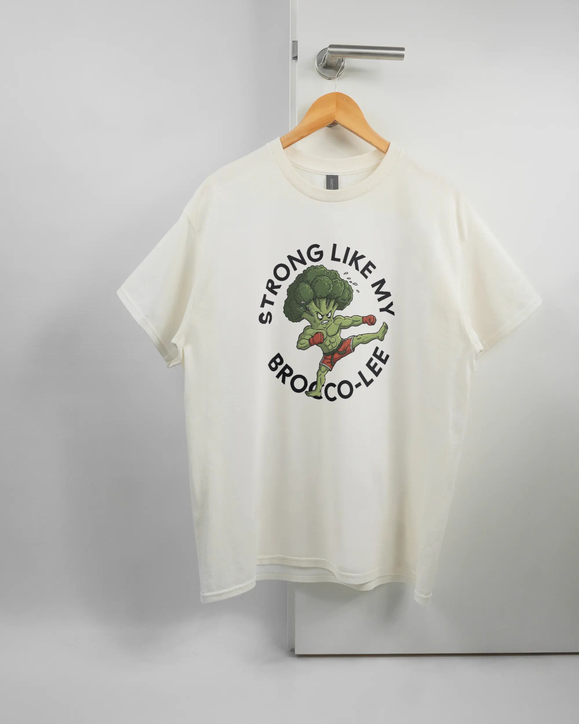 Vorderseite des Basic Unisex T-Shirt Regular von Maondo mit dem Design Brocco-Lee in der Farbe White und in der Größe L auf einem Bügel an der Türklinke aufgehängt