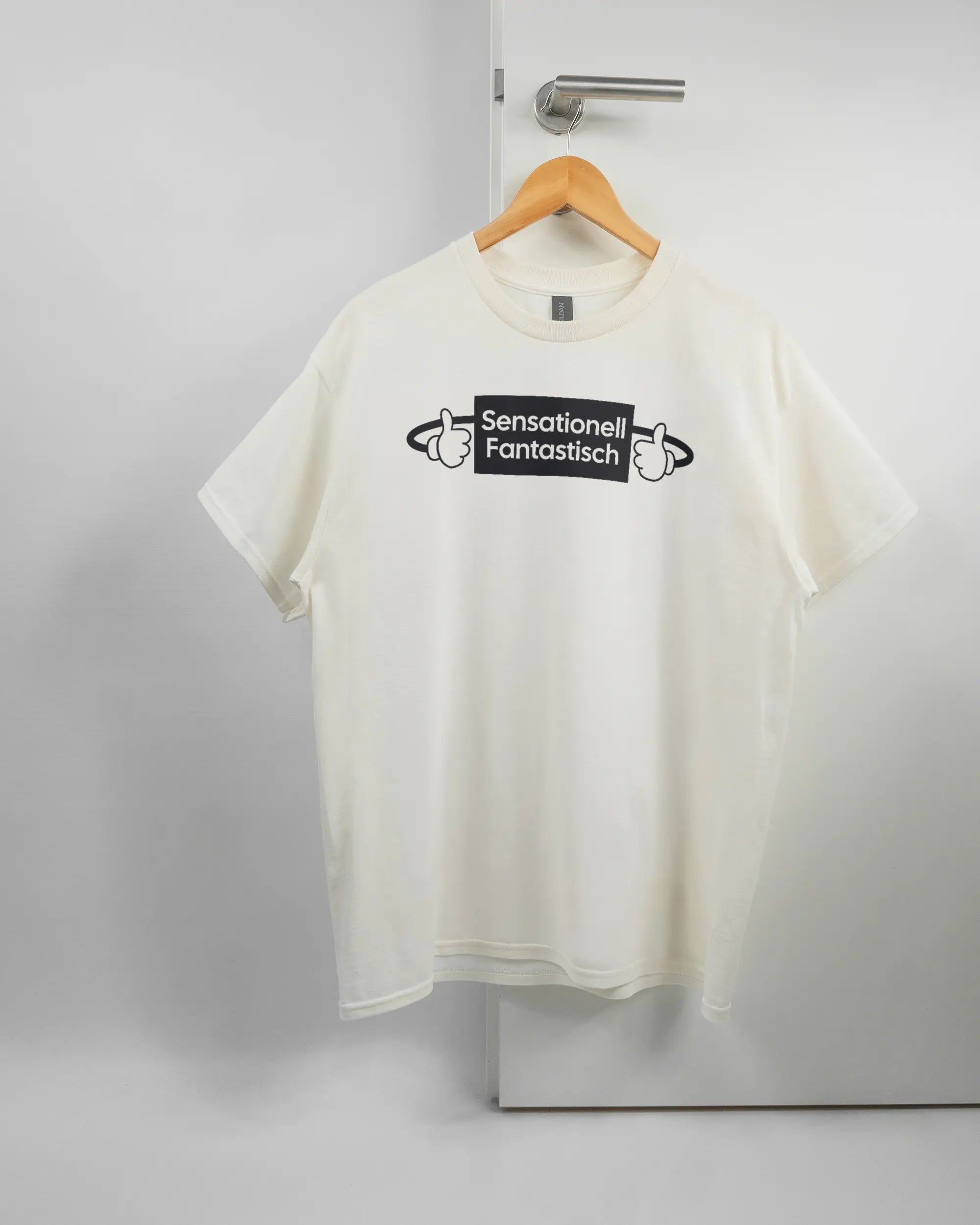 Vorderseite des Basic Unisex T-Shirt Regular von Maondo mit dem Design Fantastisch in der Farbe White und in der Größe L auf einem Bügel an der Türklinke aufgehängt