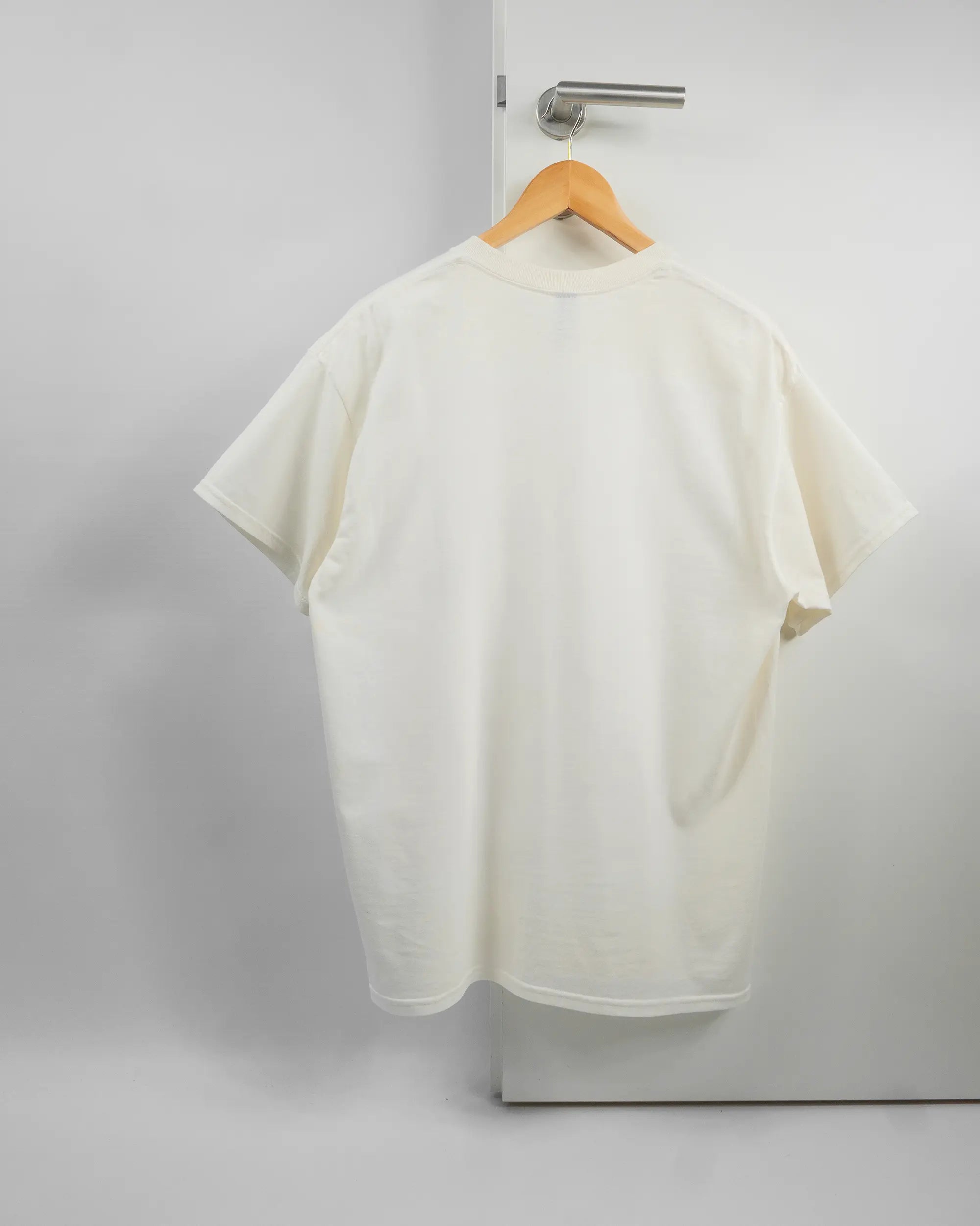 Rückseite des Basic Unisex T-Shirt Regular von Maondo ohne Motiv in der Farbe White und in der Größe L auf einem Bügel an der Türklinke aufgehängt