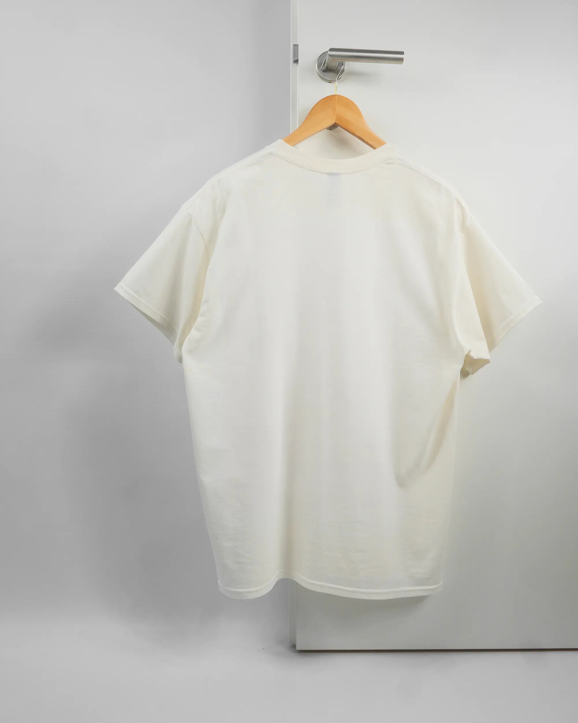 Rückseite des Basic Unisex T-Shirt Regular von Maondo ohne Motiv in der Farbe White und in der Größe L auf einem Bügel an der Türklinke aufgehängt