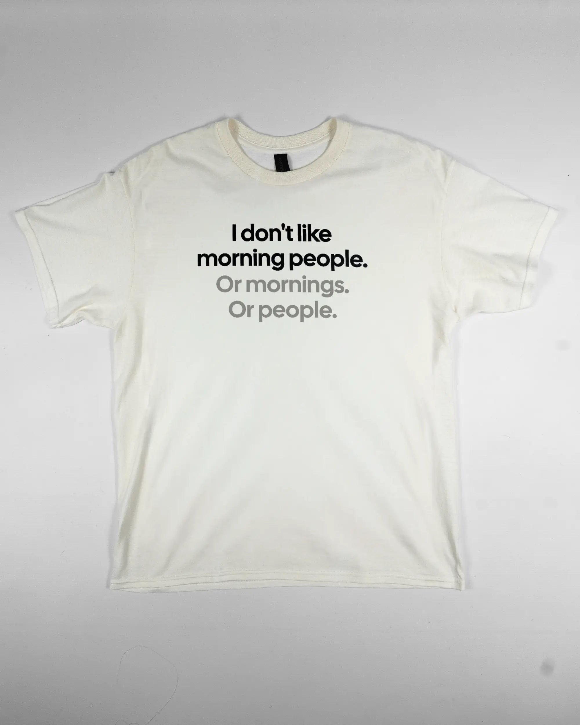 Vorderseite des Basic Unisex T-Shirt Regular von Maondo mit dem Design Morning Person in der Farbe White und in der Größe L flach auf den Boden gelegt