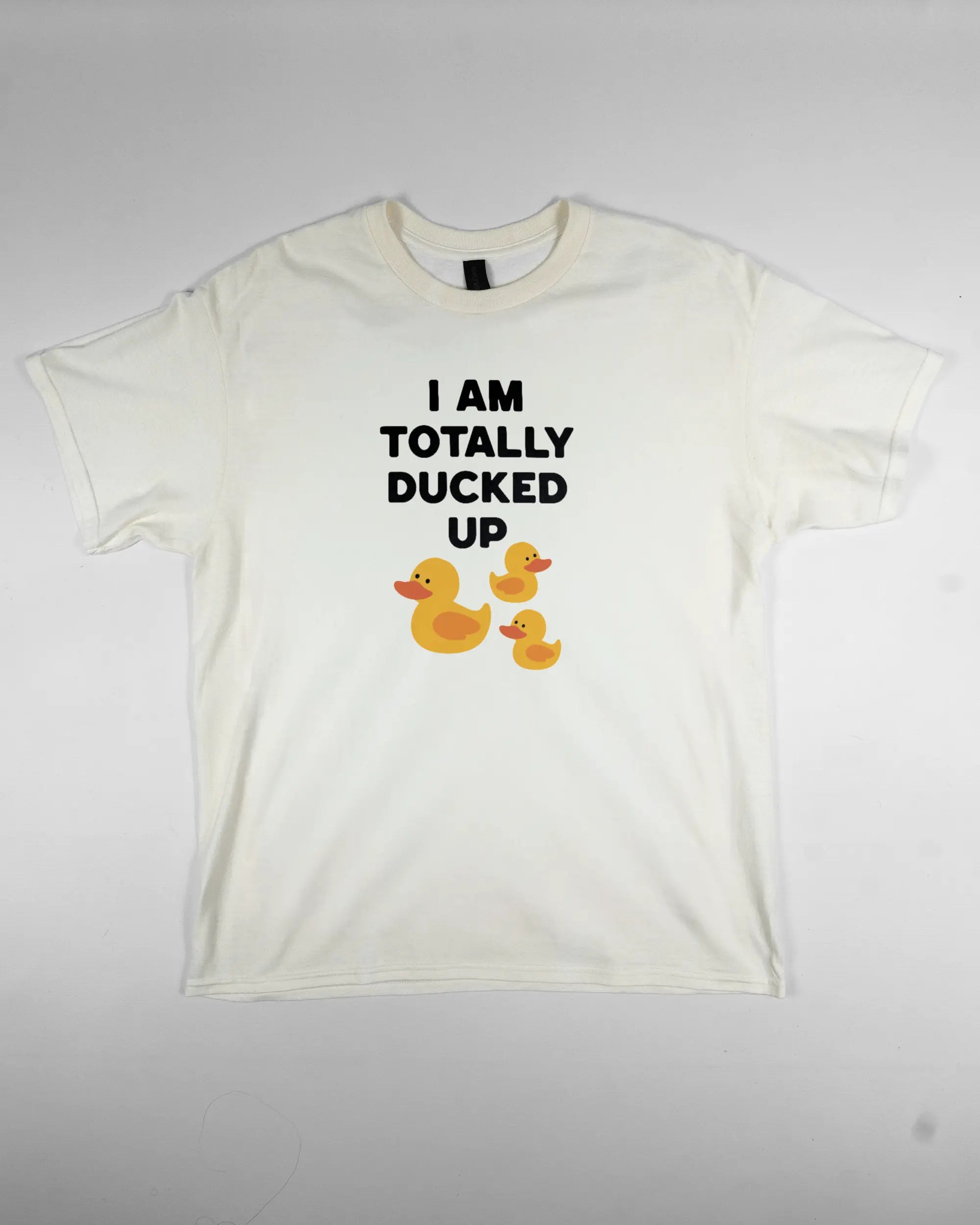 Vorderseite des Basic Unisex T-Shirt Regular von Maondo mit dem Design Ducked Up in der Farbe White und in der Größe L flach auf den Boden gelegt